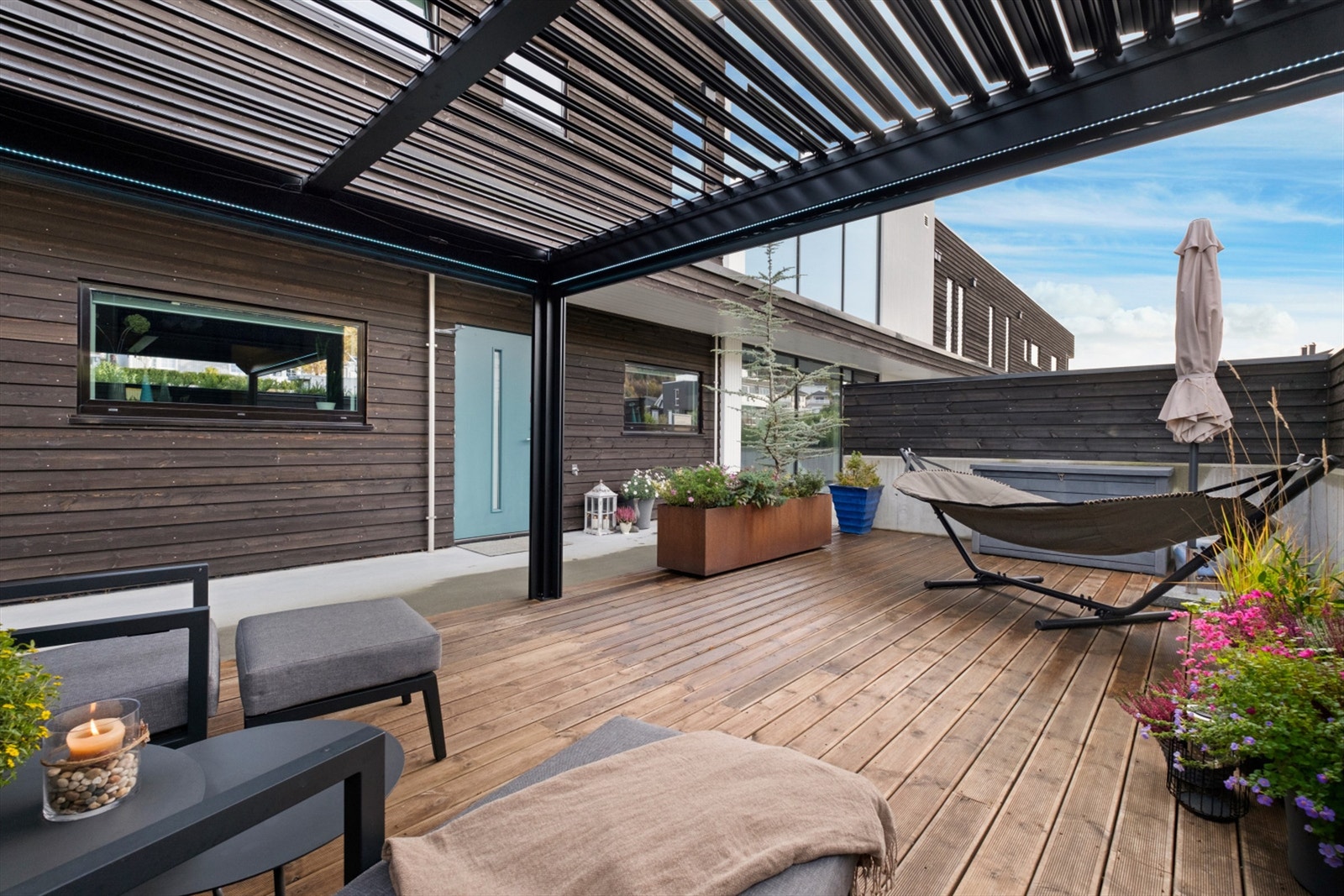 Flott uteplass med pergola skjermet med levegger av betong og tre Galleribilde