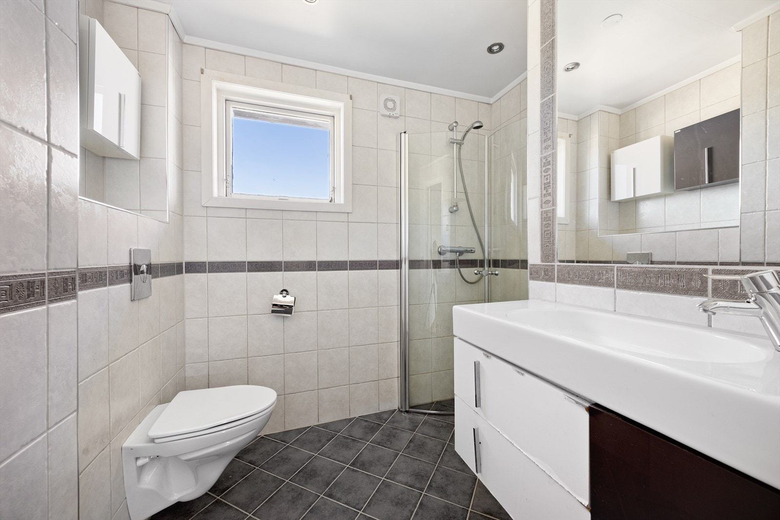På badet er både vegger og gulv flislagt, og det er installert varmekabler i gulvet. Galleribilde