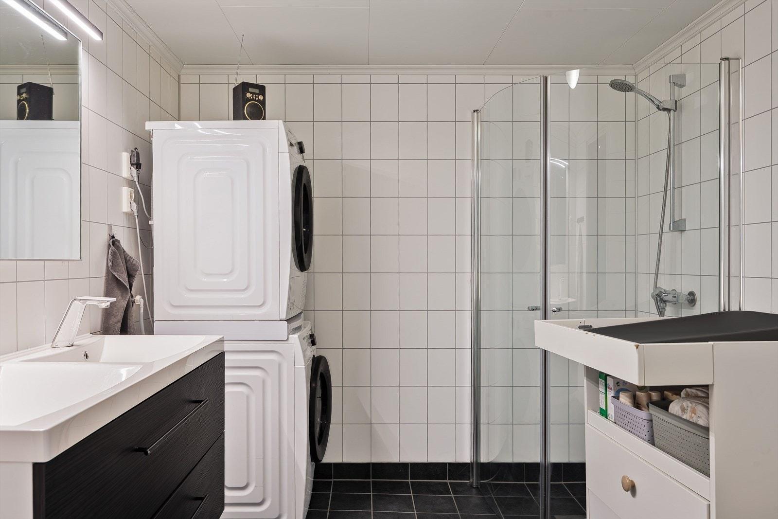 Leiligheten har et lyst og moderne baderom fra byggeåret 2013. Baderommet har mørke fliser på gulv med gulvvarme, hvite fliser på veggene og avtrekk via balansert ventilasjon. I hjørnet er det plass og opplegg for vaskemaskin/tørketrommel. Galleribilde