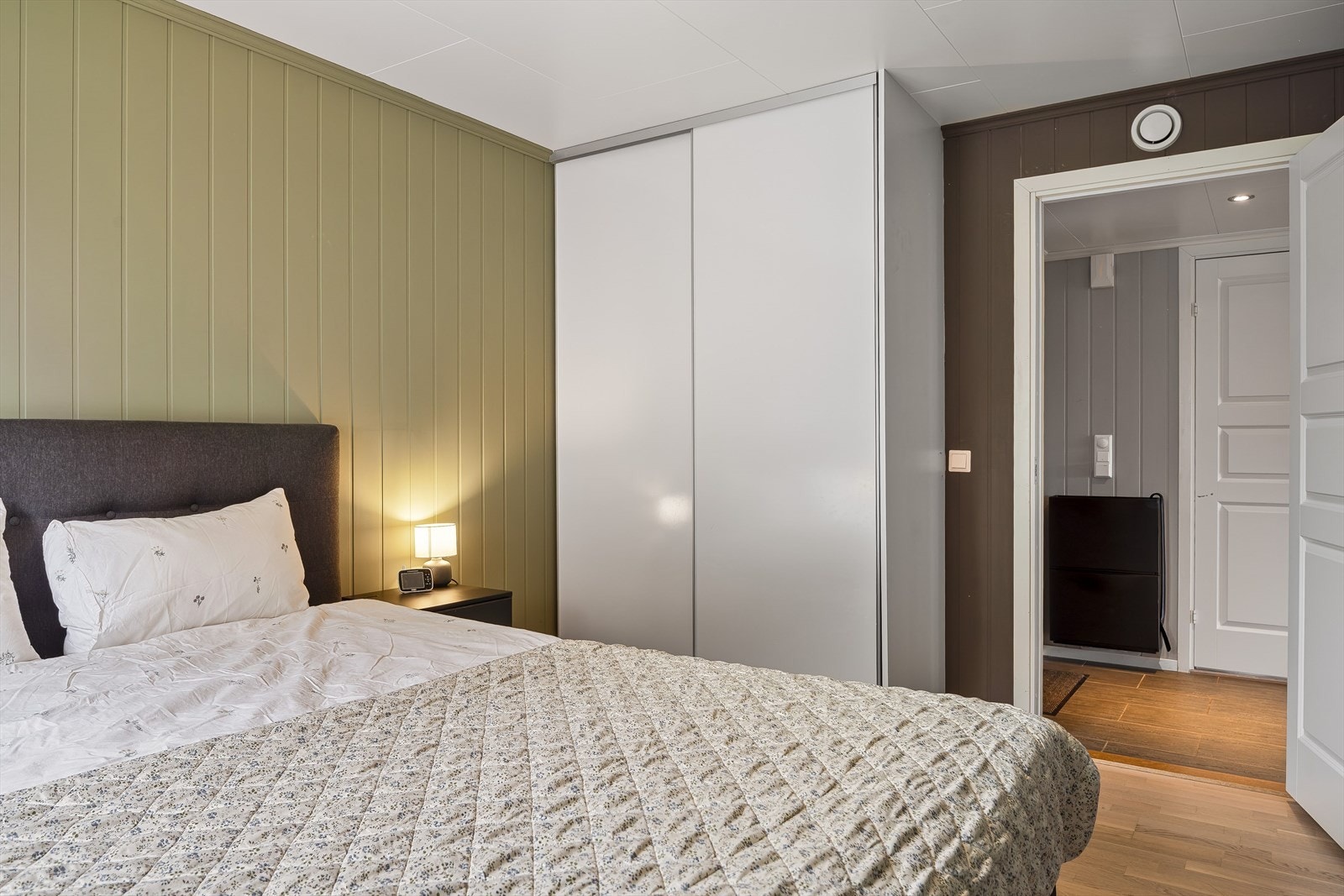 På soverommet er det naturlig plass til dobbeltseng med tilhørende nattbord, samt god oppbevaringsplass i plassbygget skyvedørsgarderobe. Galleribilde