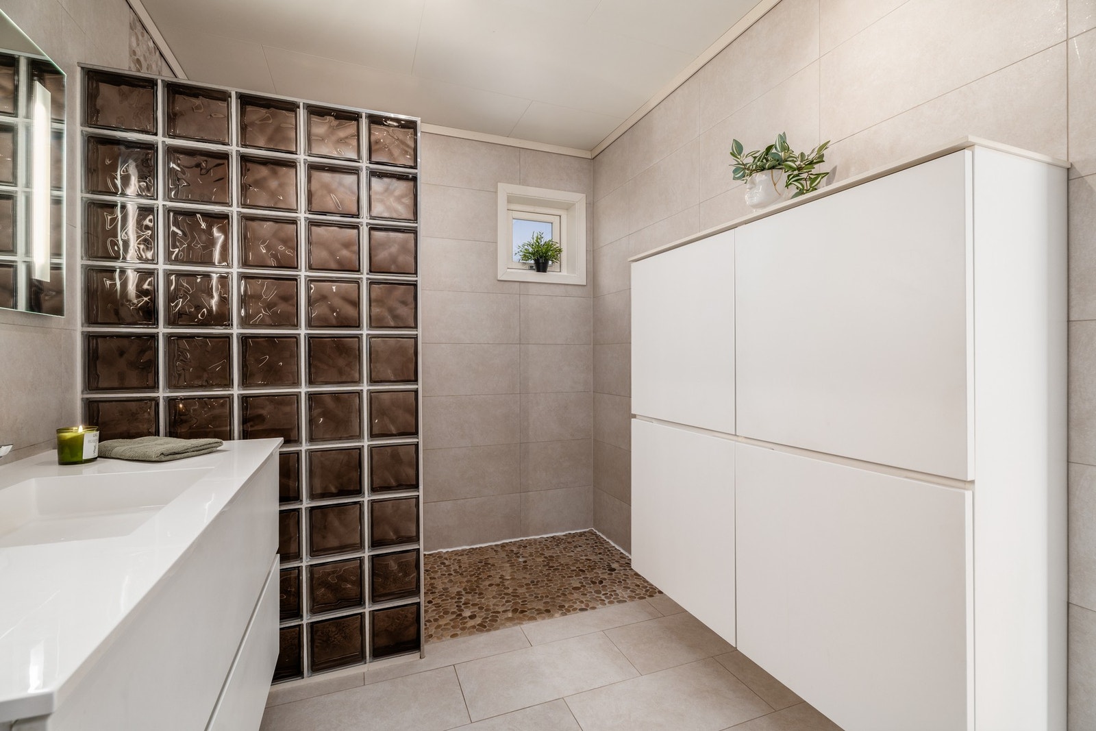 Badet er flislagt og har varmekabler i gulvet, vegghengt toalett, servant og dusj. Galleribilde