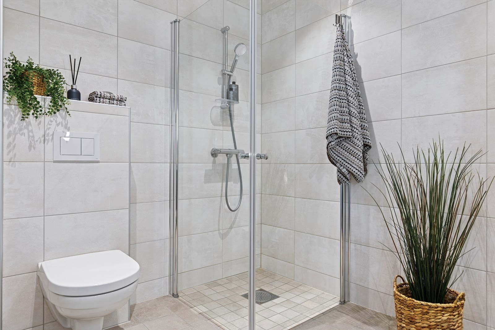 Badet er flislagt med gulvvarme og er utstyrt med vegghengt klosett og innfellbare dører i dusjsonen. Galleribilde