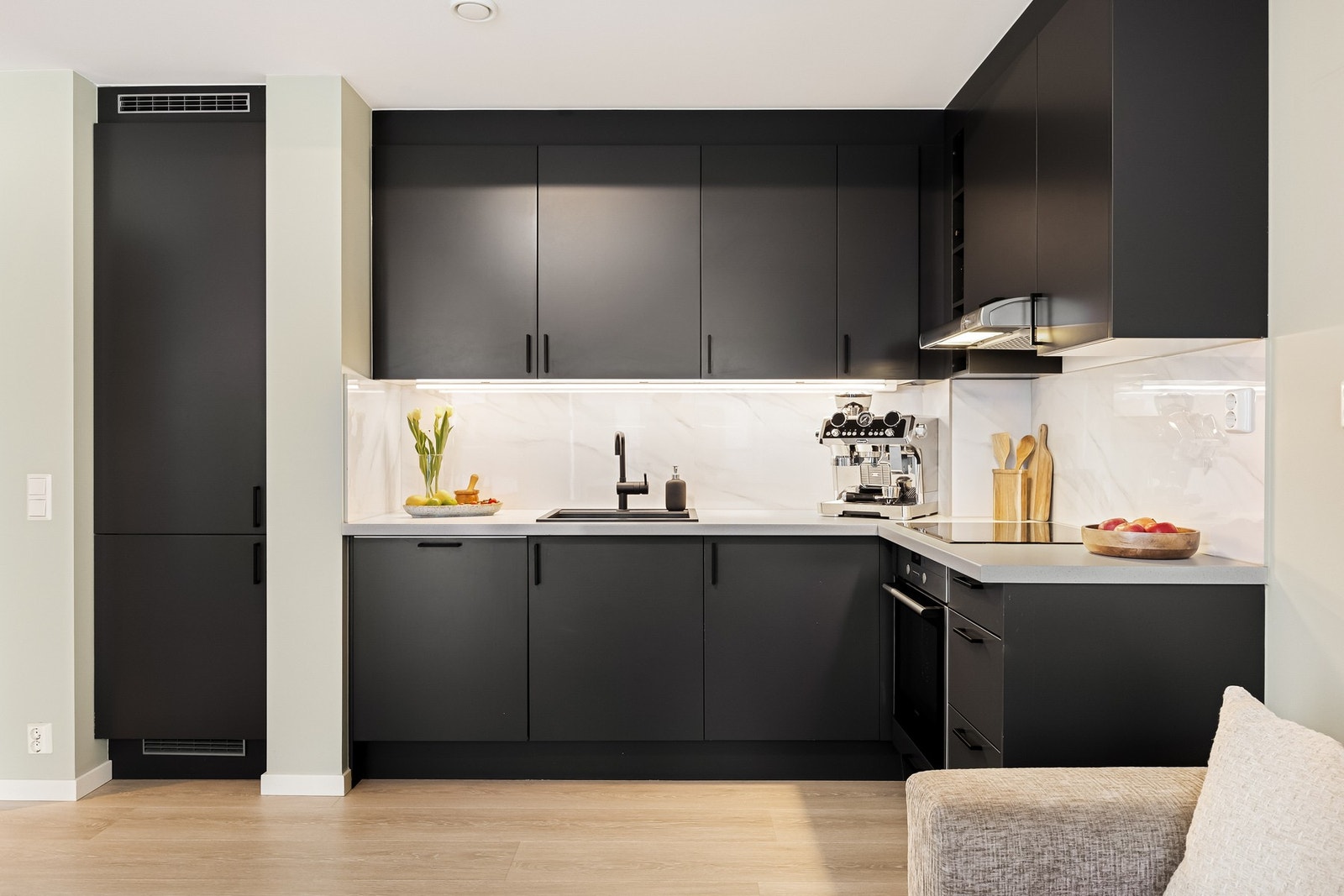 Innredningen har slette, mørke fronter som står i fin kontrast til lyse benkeplater og backsplash, og skaper et tidløst og elegant uttrykk. Galleribilde