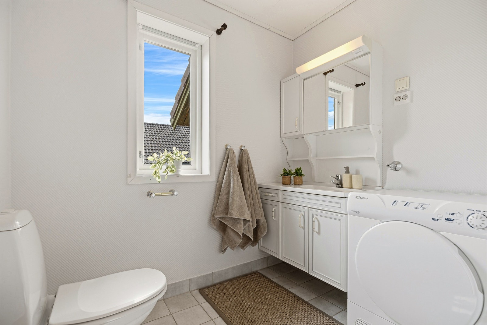 Innredningen gir badet gode brukskvaliteter i det daglige, med plass til både oppbevaring og vaskemaskin. Galleribilde