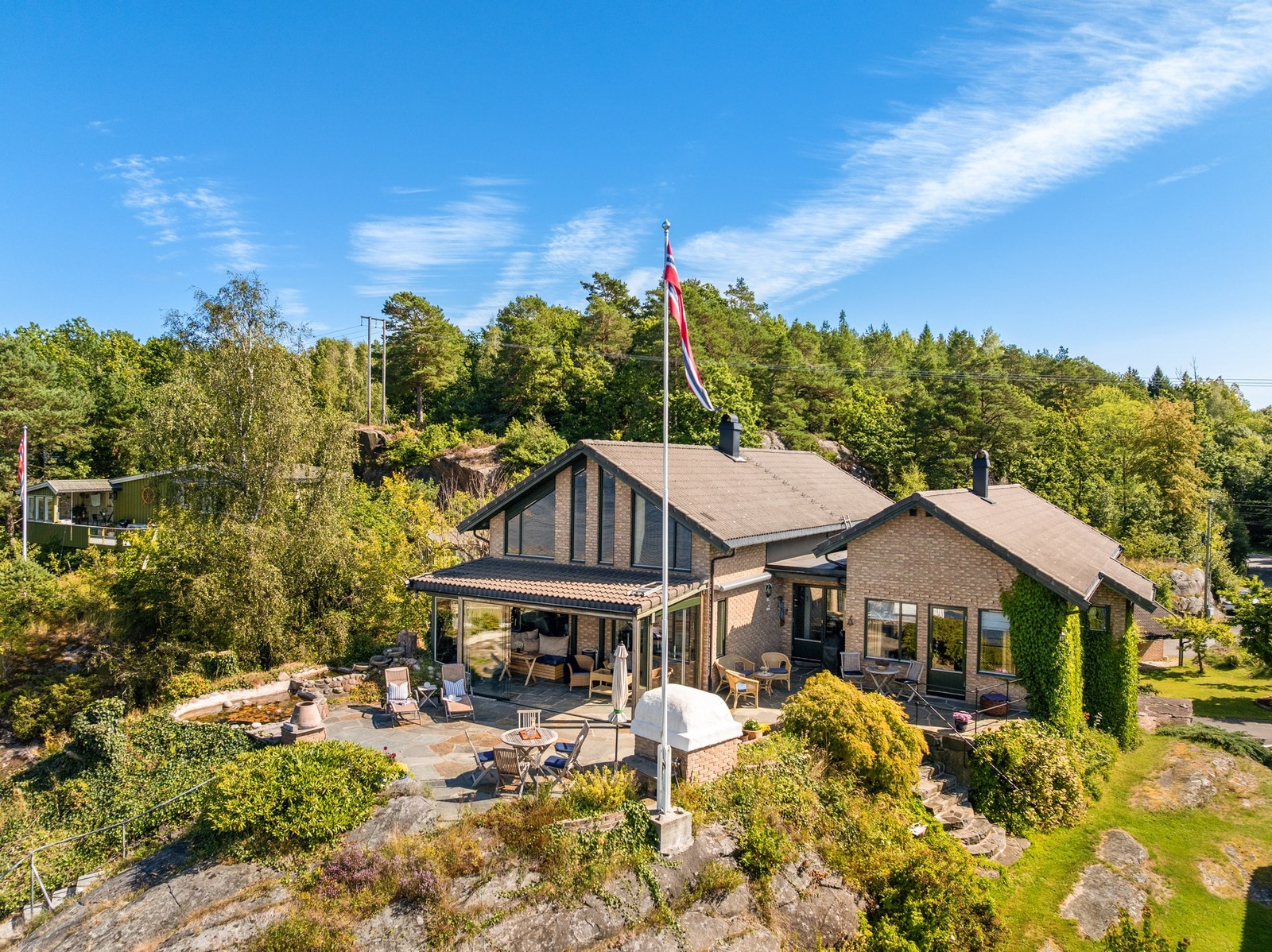 Eiendommen har en markant plassering i terrenget, med flere soner for opphold både ved boligen og nede ved sjøen. Galleribilde