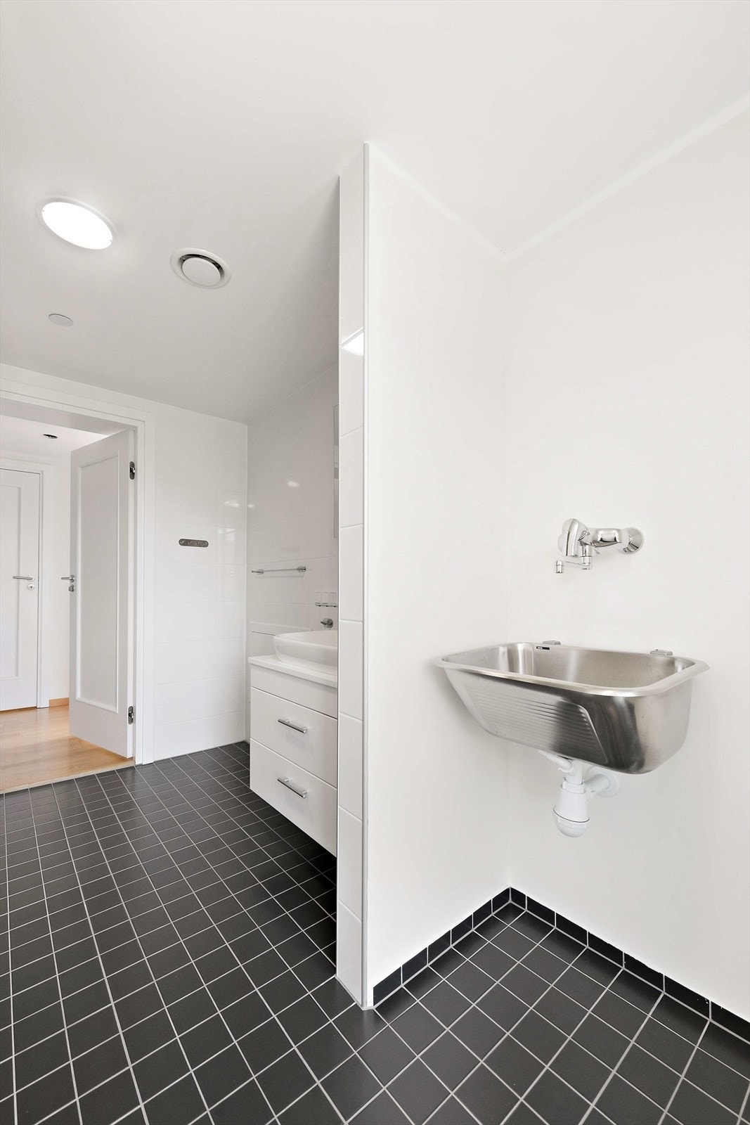 Vaskeromsdelen er utstyrt med skyllekar og opplegg for vaskemaskin mens badet er utstyrt med baderomsinnredning, toalett og dusjveggerhjørne. Galleribilde