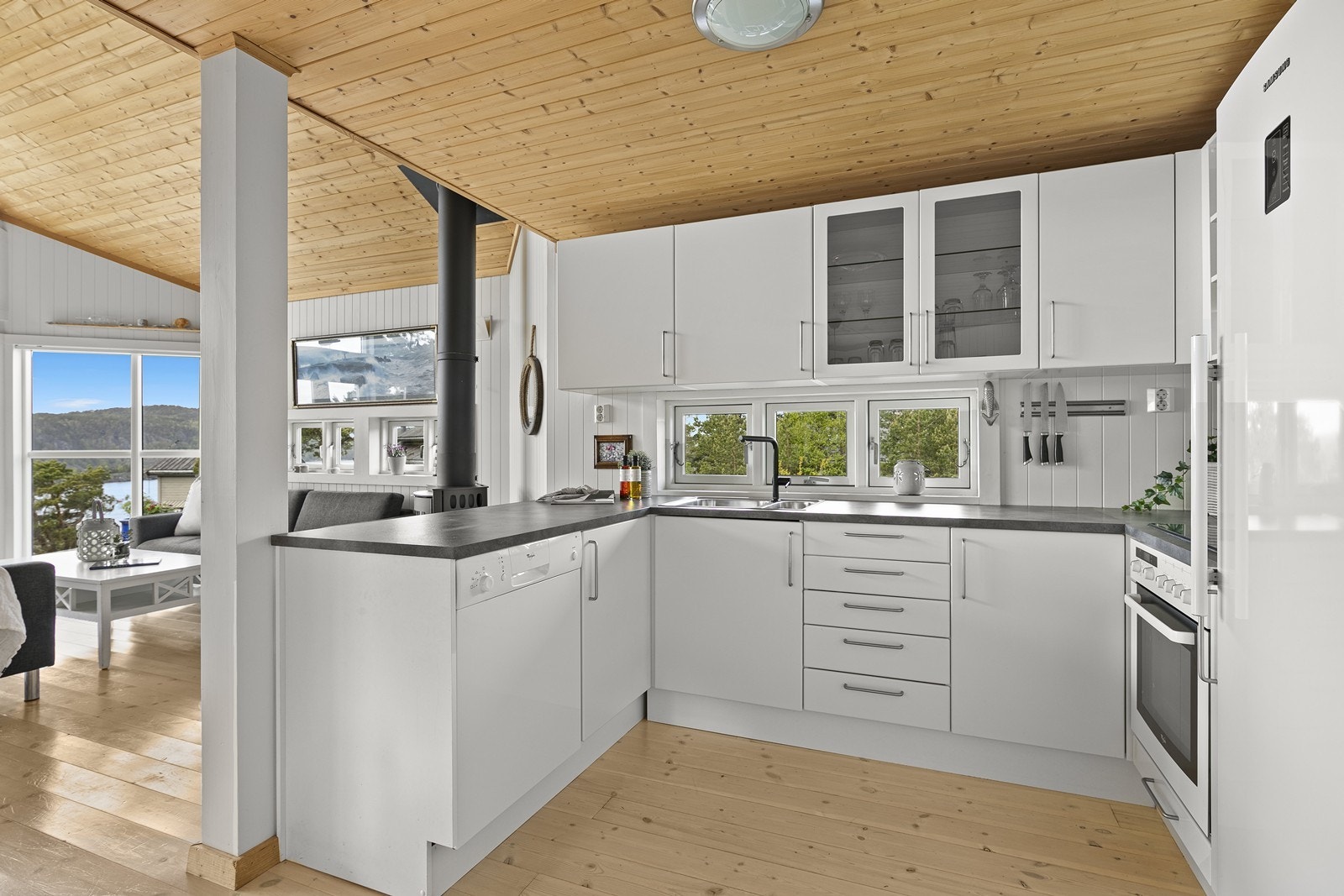Kjøkkenet har en innredning med hvite fronter, laminert benkeplate og integrert komfyr/platetopp samt frittstående kjøleskap og oppvaskmaskin. Galleribilde