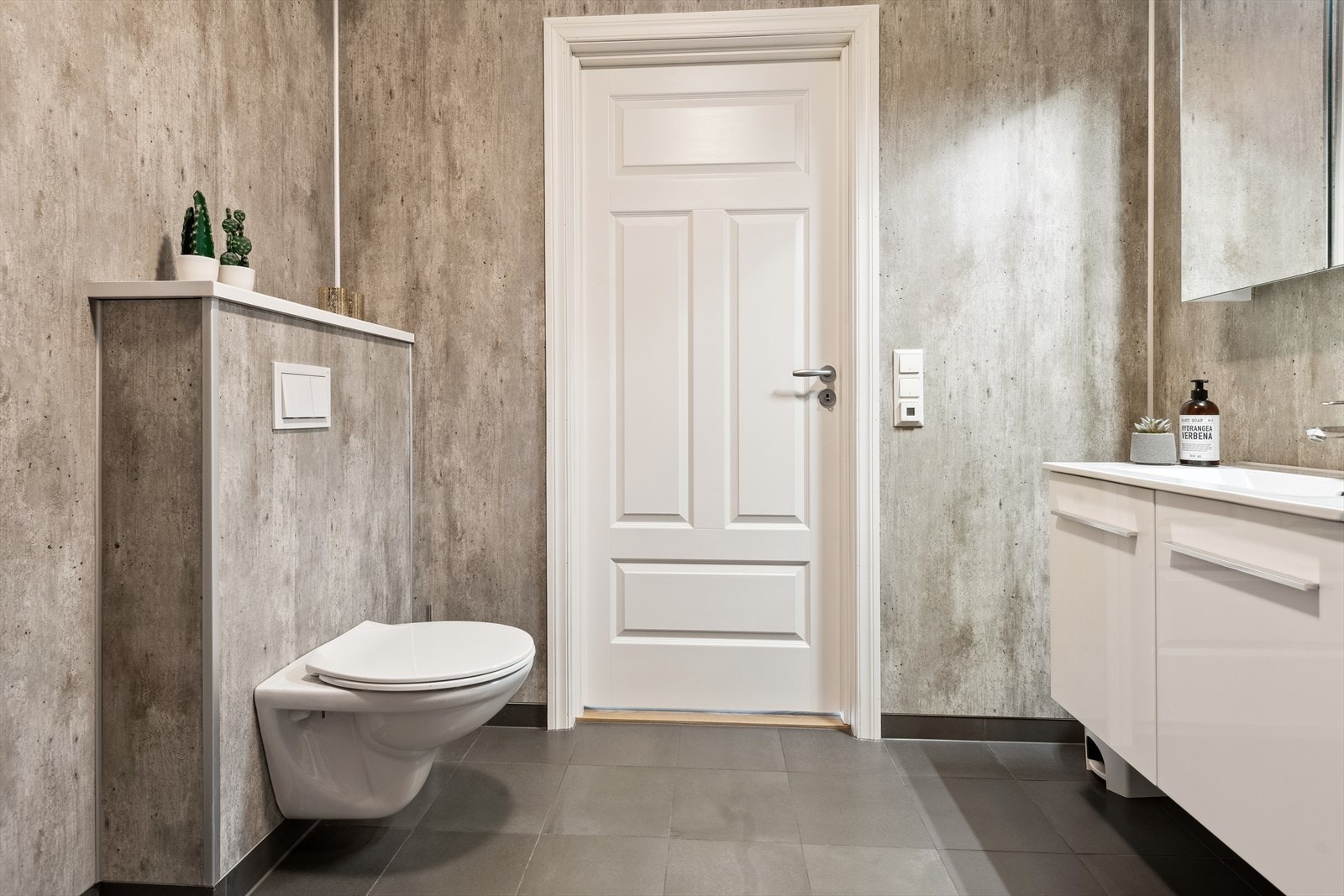 Badet har vegghengt toalett med skjult sisterne og heldekkende servant i skapinnredning. Galleribilde