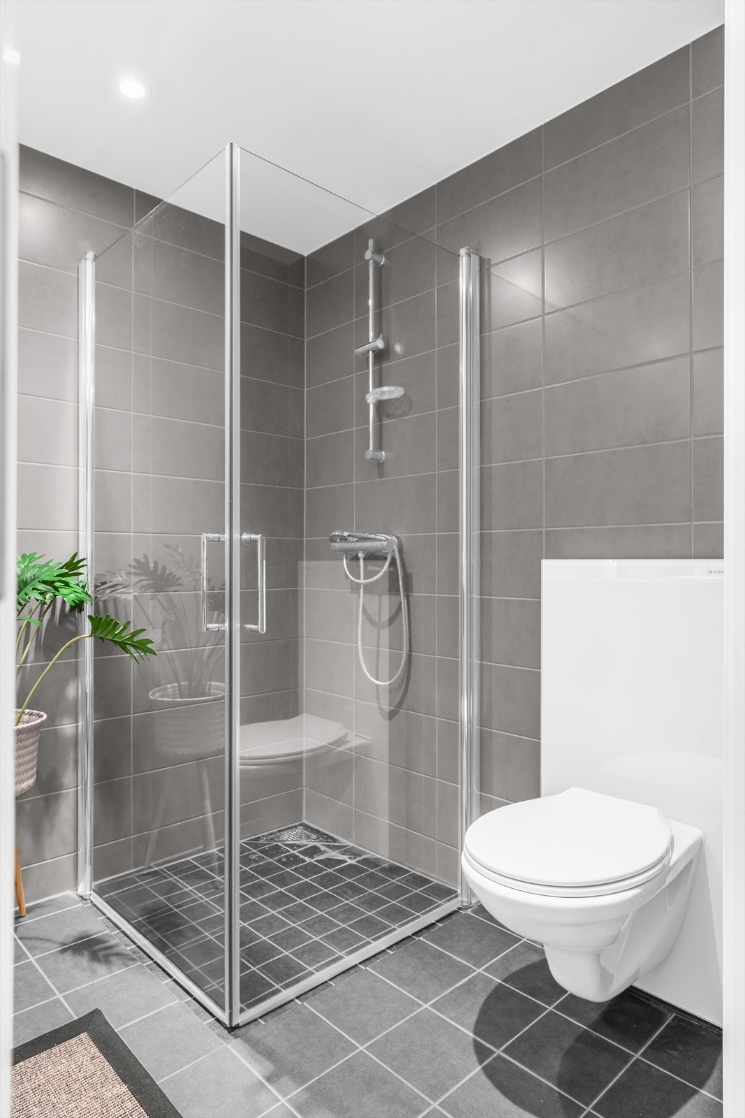 Badet er utstyrt med veggmontert toalett, speilskap med overliggende belysning, baderomsinnredning med malte fronter og laminat benkeplate med nedfelt servant. Galleribilde
