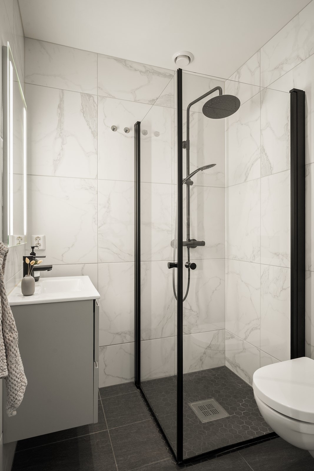Stilrent og lekkert bad med flislagte vegger og gulv. Badet i boligens første etasje ligger praktisk til med adkomst direkte fra gangen. Galleribilde