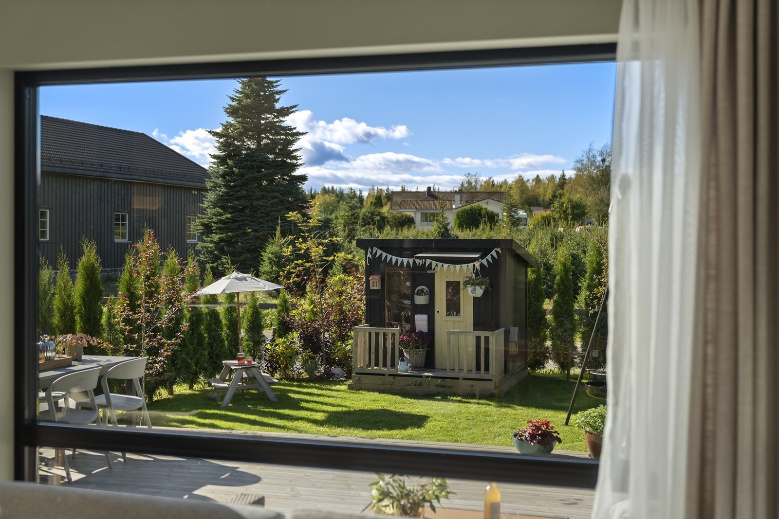 Pent opparbeidet uteområde med terrasse, hage og dukkestue. Galleribilde