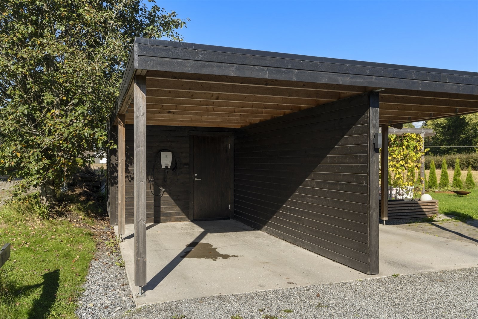 Carport med elbillader og tilhørende sportsbod gir praktisk lagringsplass. Galleribilde