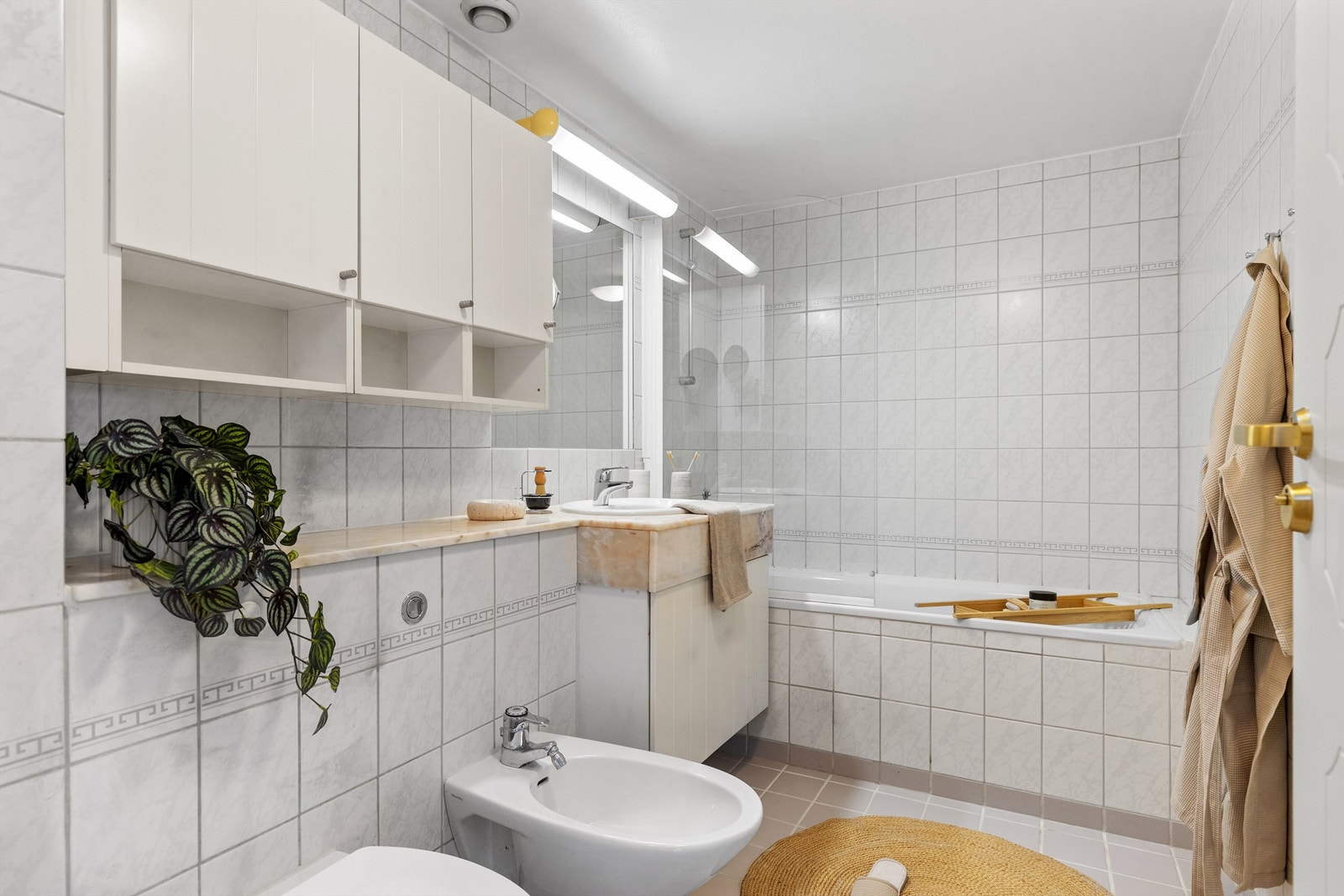 Badet har en vegghengt servantinnredning med speil og overlys, samt et praktisk vegghengt skap for oppbevaring. Galleribilde