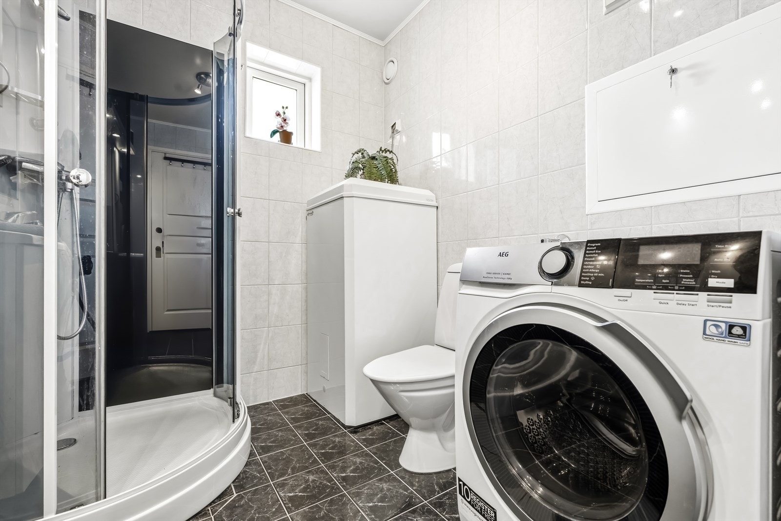 Badet har dusjkabinett og opplegg for vaskemaskin Galleribilde