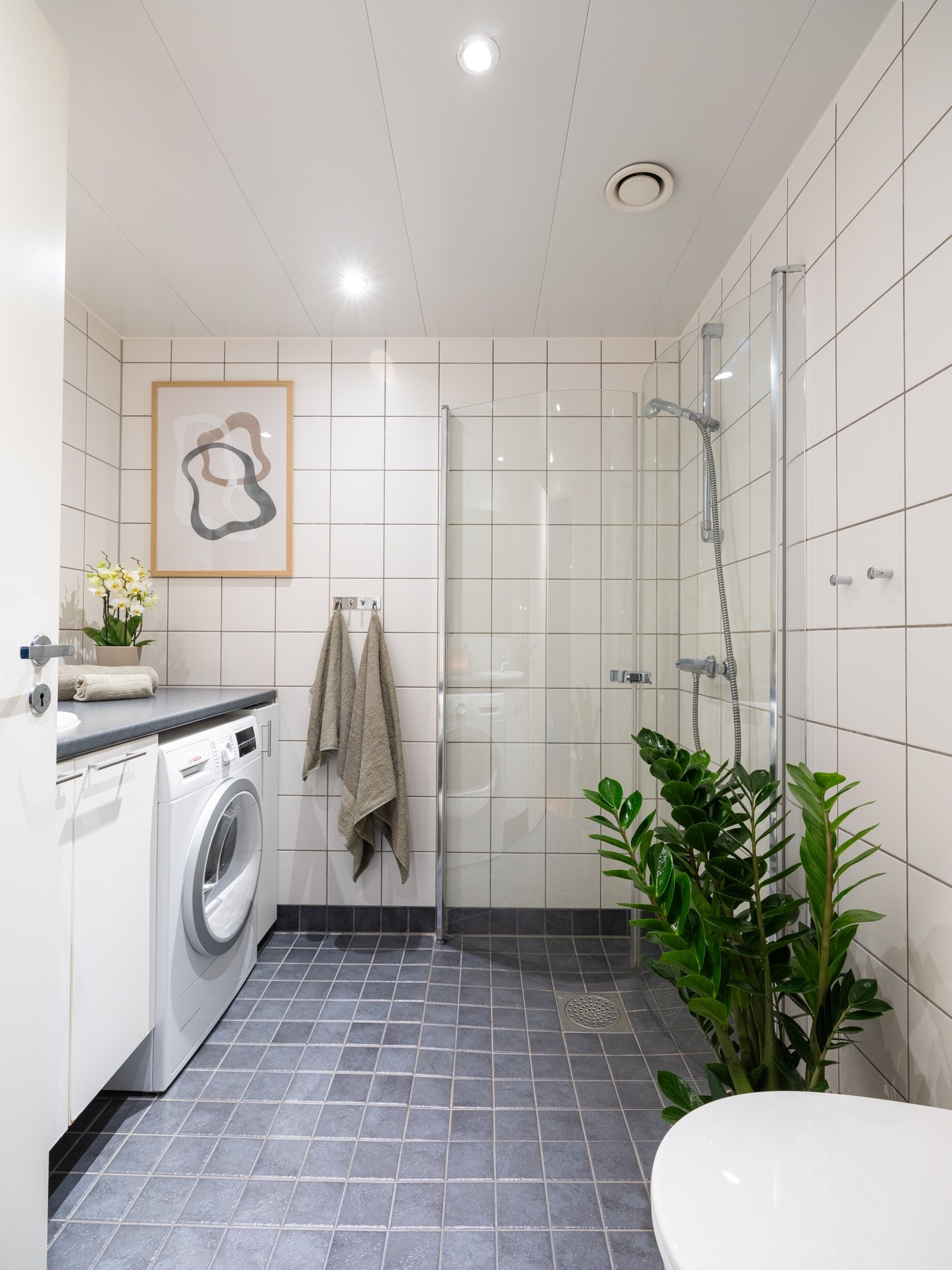 Badet i boligen fremstår i klassisk utførelse fra byggeår, med et tidløst uttrykk og praktiske løsninger. Rommet har flislagt gulv med behagelig gulvvarme, samt flislagte vegger som gir et stilrent og lettstelt preg. Galleribilde