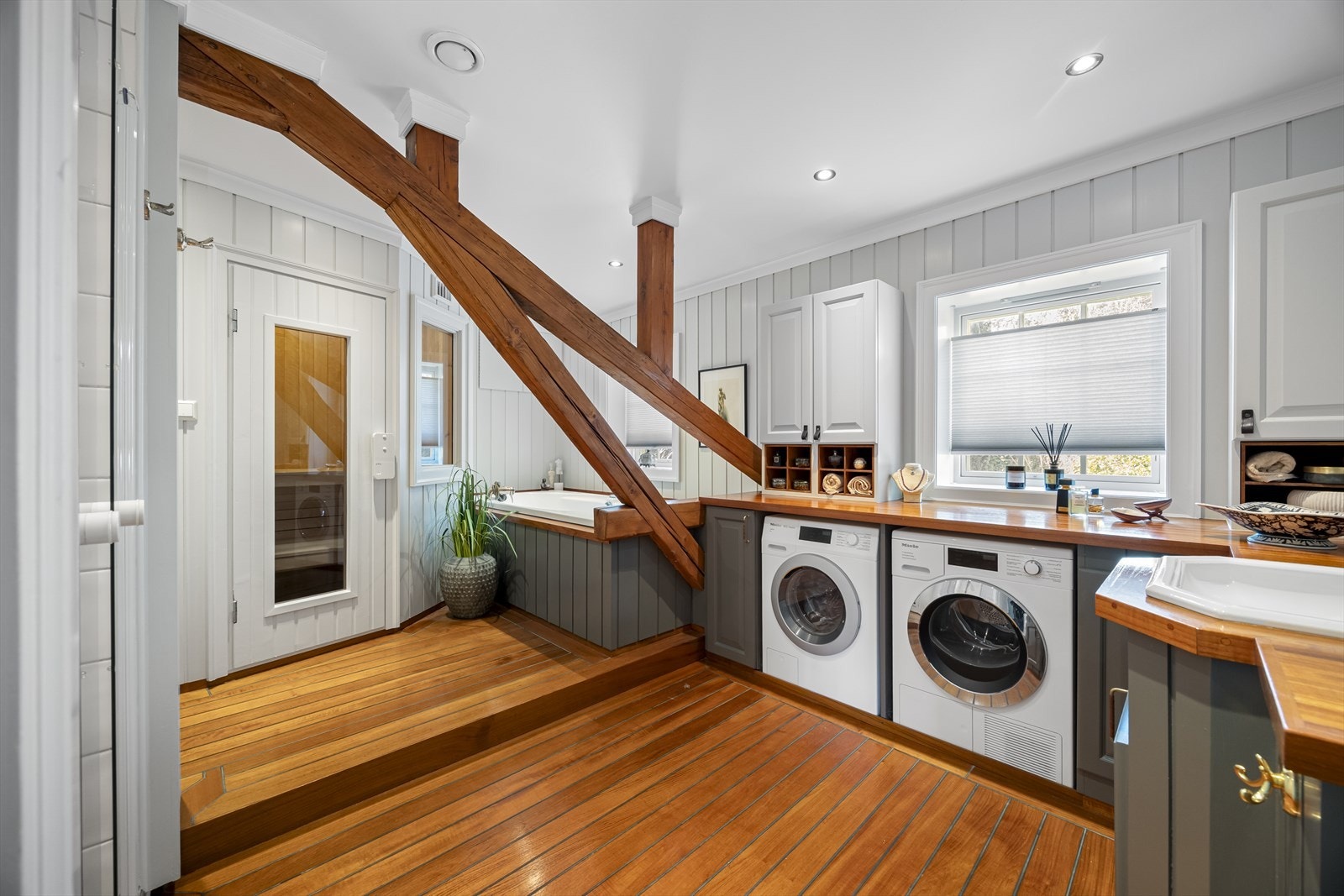 Badet har klassiske skipsgulv og vegger med malt panel. Tak er pusset og malt med downlights og det er synlig bindingsverk med takbjelker. Galleribilde