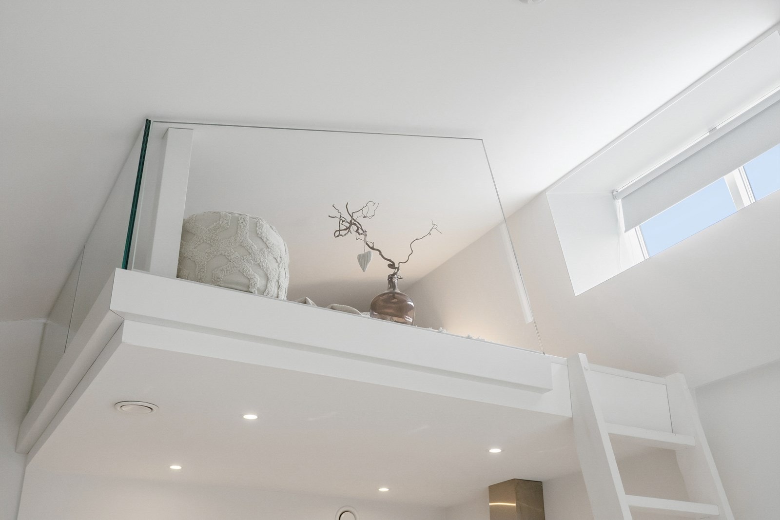 Hemsen er sikret med glassrekkverk og gir en visuell forbindelse ned til kjøkkenet og stuen. Galleribilde