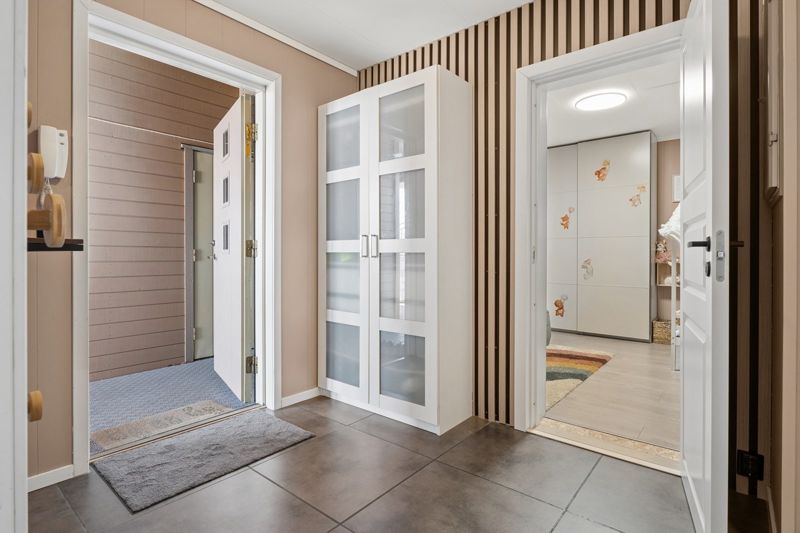Entréen ønsker velkommen med flislagt gulv og gir direkte tilgang til ett av badene og det ene soverommet. Galleribilde