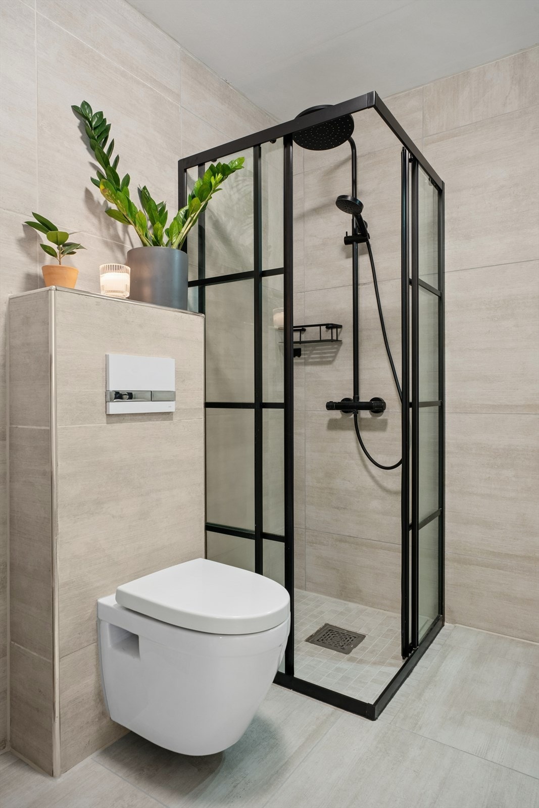Badet ved entréen har en stilren dusjnisje med foldedører, vegghengt toalett og heldekkende servantinnredning. Galleribilde