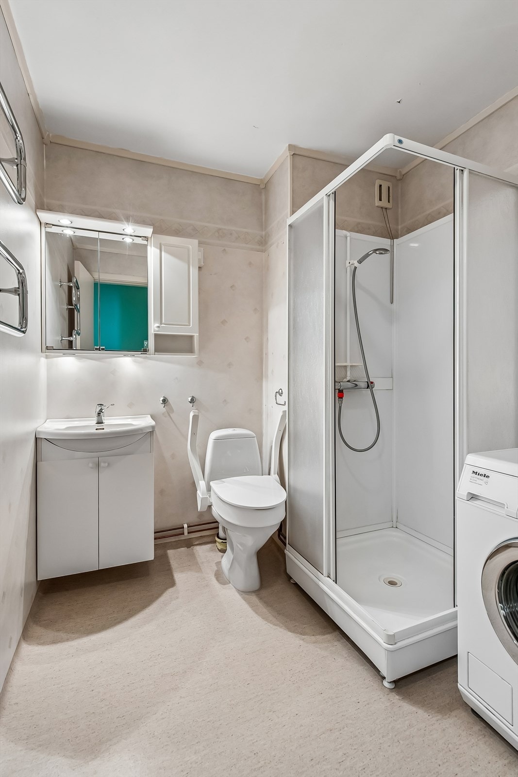 Badet er innredet med dusjkabinett, gulvmontert toalett og servant med underskap. Galleribilde