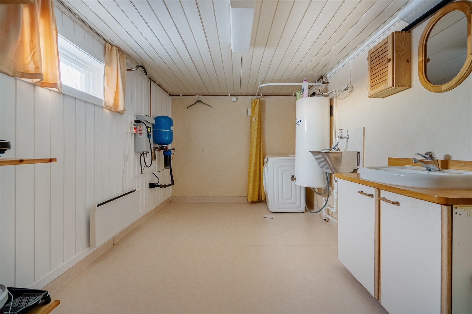 Praktisk vaskerom i kjelleren. 150L varmtvannsbereder, gjort plass til vaskemaskin og innredning med overliggende servant med lys over speil. Galleribilde