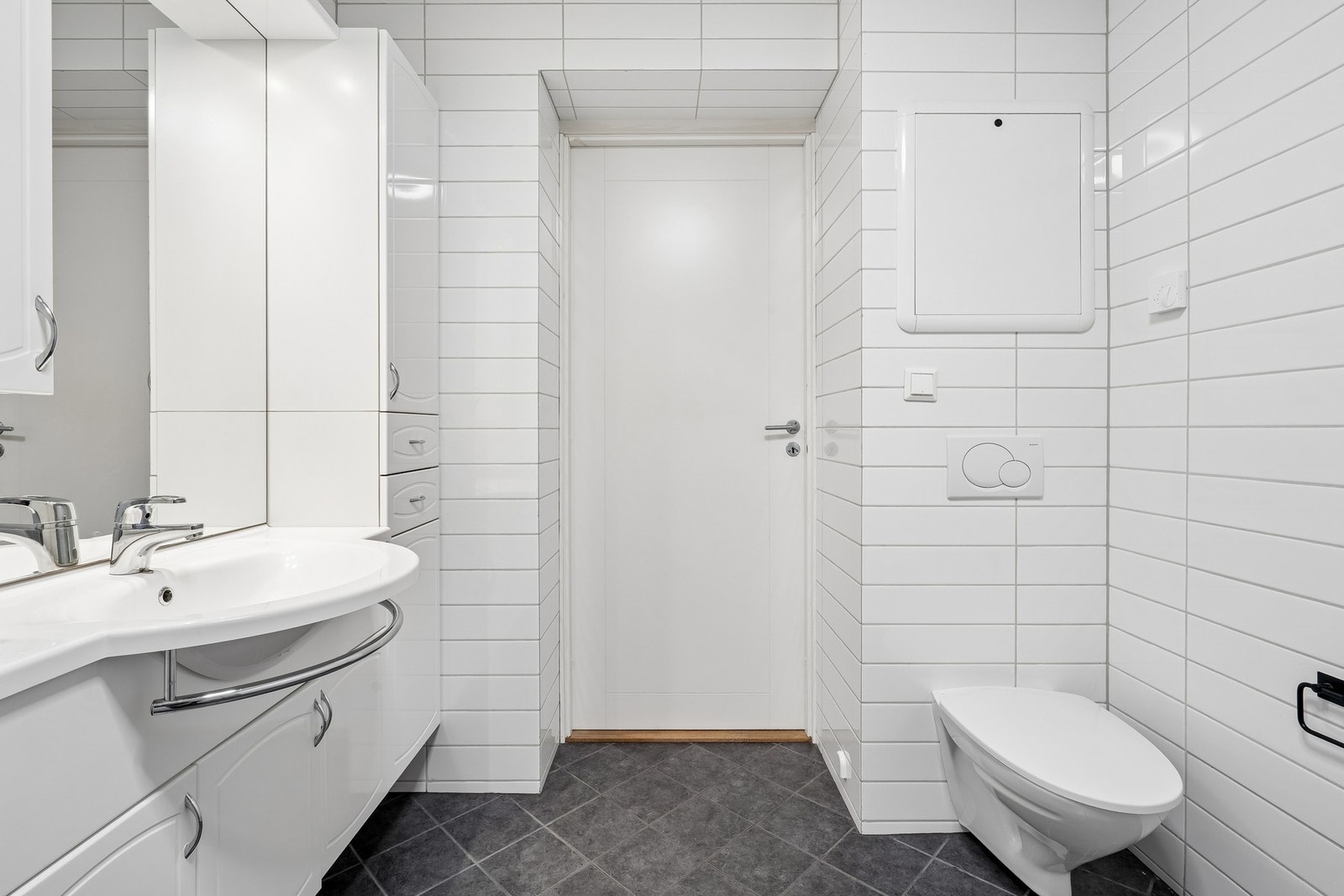 Baderommet har servant i innredning, veggmontert toalett, dusjplass med dusjvegg og opplegg for vaskemaskin. Galleribilde