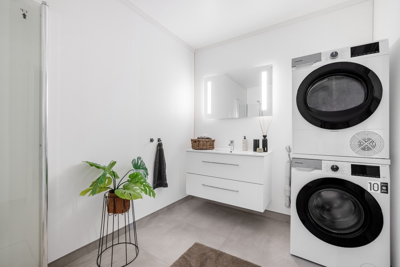 Innbydende baderom med flislagt gulv med varmekabler. Badet er innredet med heldekkende servant over skuffeinnredning, speilskap med belysning, vegghengt skap, dusjkabinett og toalett. Galleribilde