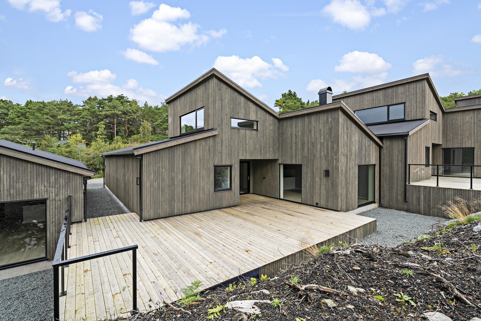Moderne arkitektur med reint og stramt uttrykk, kledd i mørkbeisa trepanel. Galleribilde