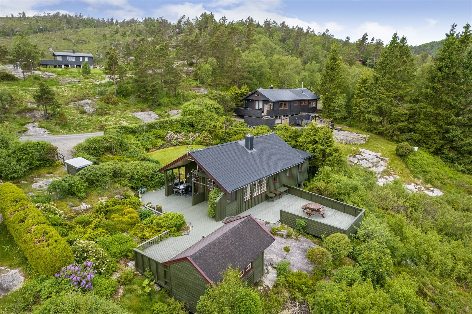 Sommerbilde fra tidligere salg. Trær er felt og området er åpnet opp rundt hytta. Galleribilde