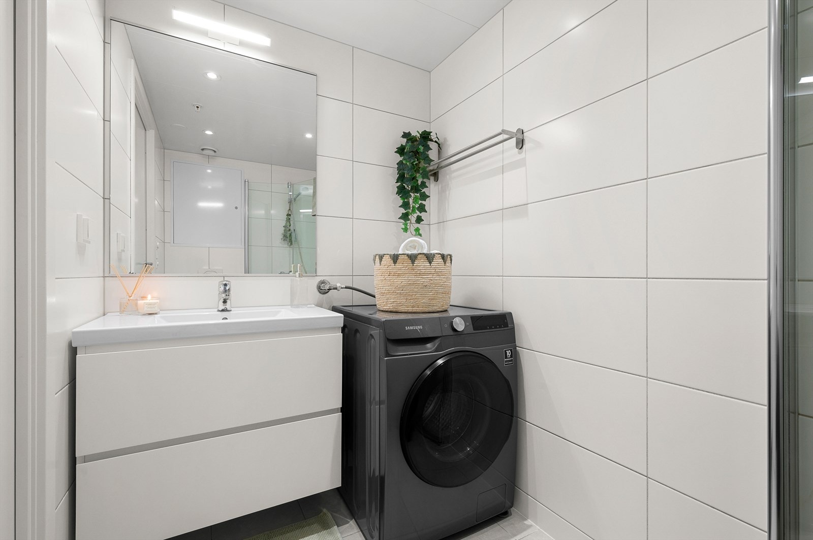 Moderne bad med stilren servant og stort speil med lys. Baderommet er utstyrt med elektrisk gulvvarme og mekanisk avtrekk. Det er også opplegg for kombinert vaskemaskin og tørketrommel. Galleribilde