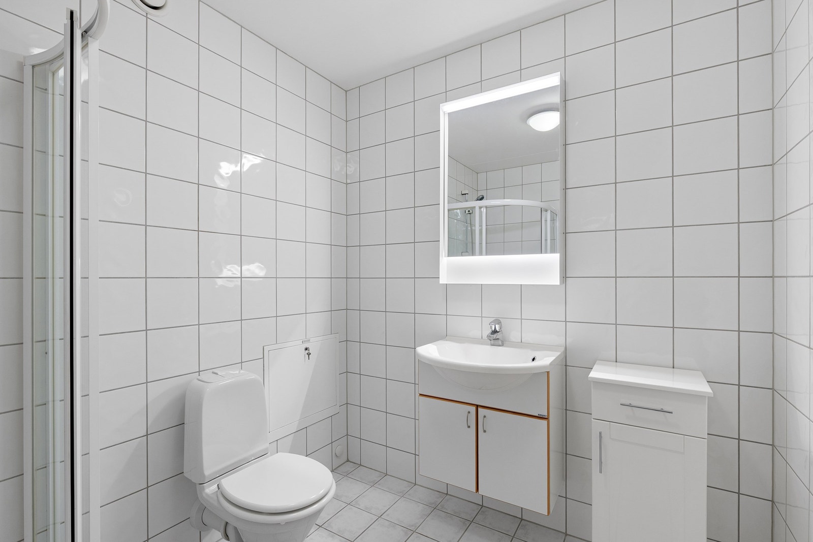 Badet er innredet med dusjhjørne, vegghengt servant med speil Galleribilde