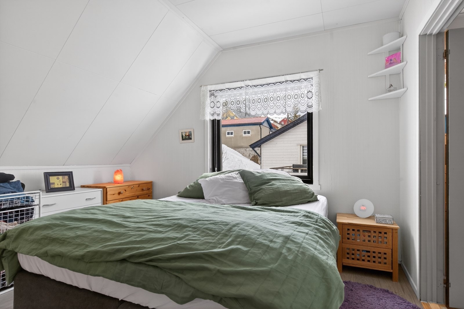 Lyst og koselig hovedsoverom med skråtak og utsikt mot nabolaget. Galleribilde