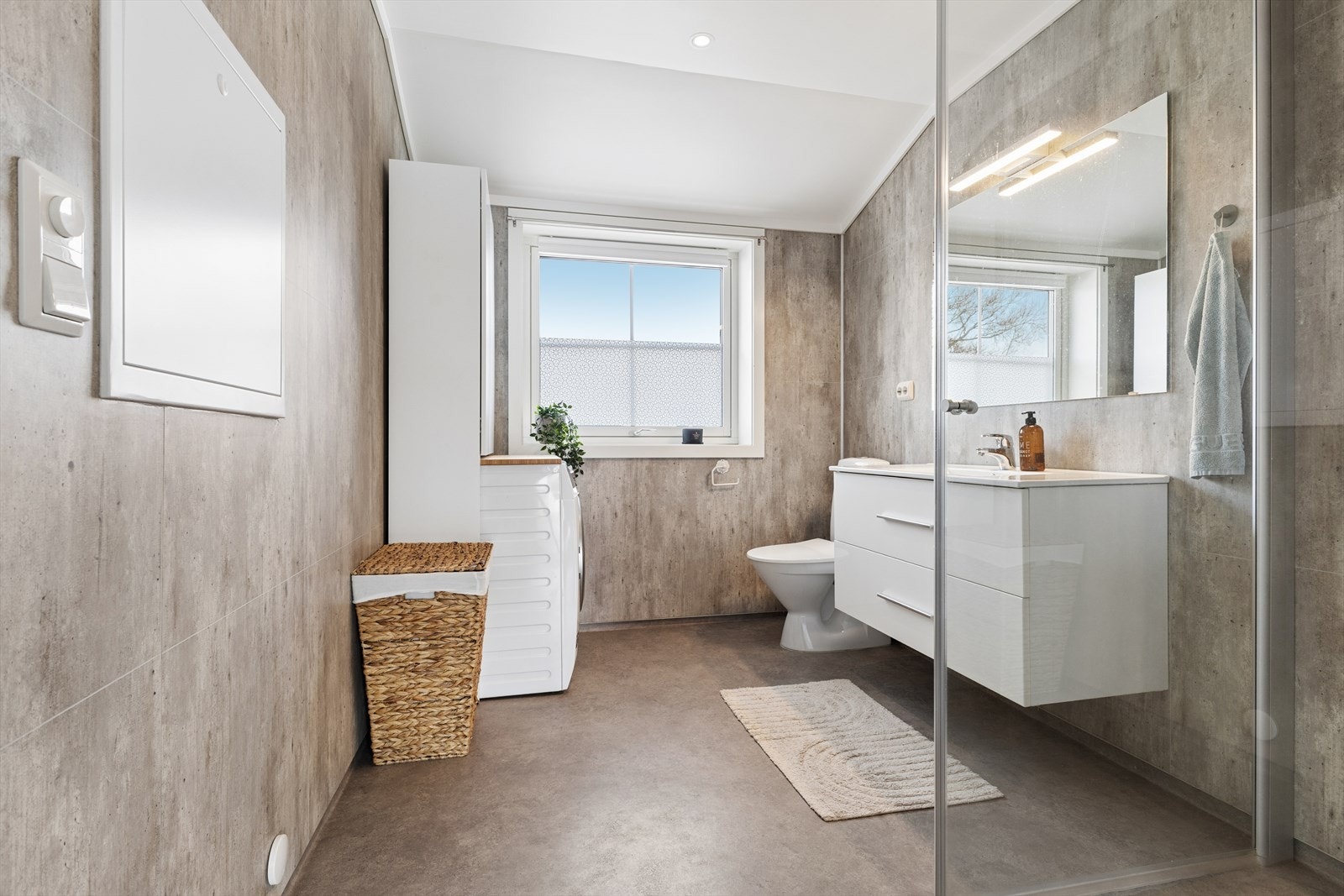 Badet har veggplater, belegg på gulv og opplegg for vaskemaskin. Galleribilde