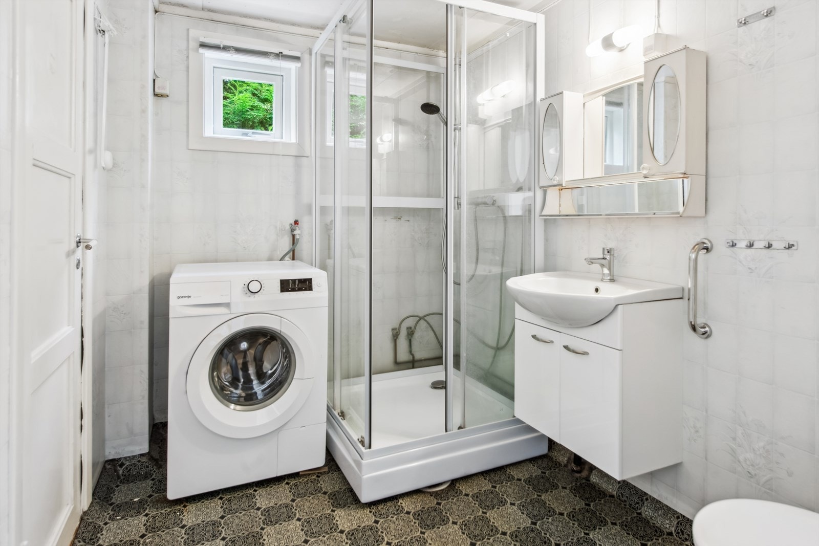 Badet er utstyrt med servant med underskap, speilskap, dusjkabinett og gulvmontert toalett. Galleribilde