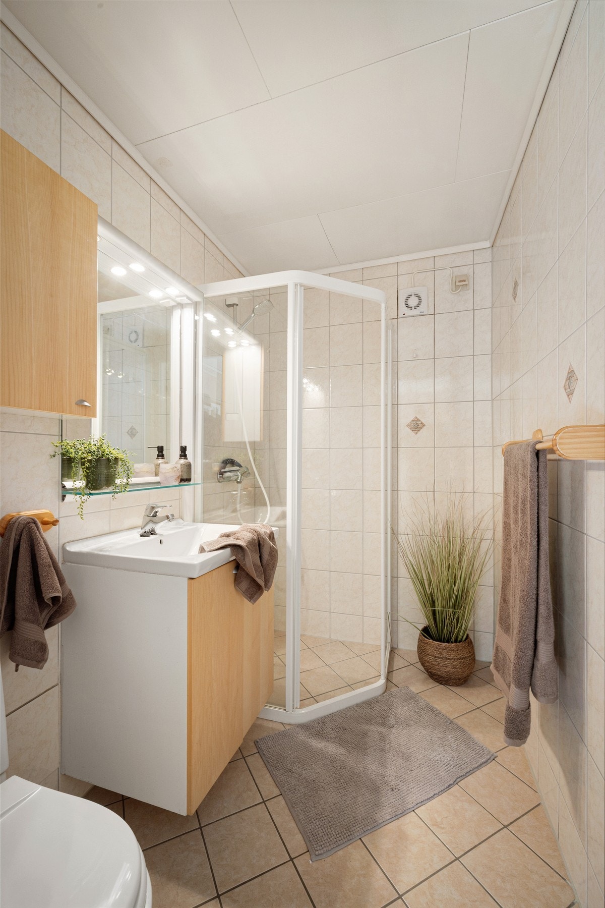 Badet er helfliset med varme i gulvet. Våtrommet har toalett, vask med under- og overskap og dusj. Rommet har spotter over speil. Galleribilde
