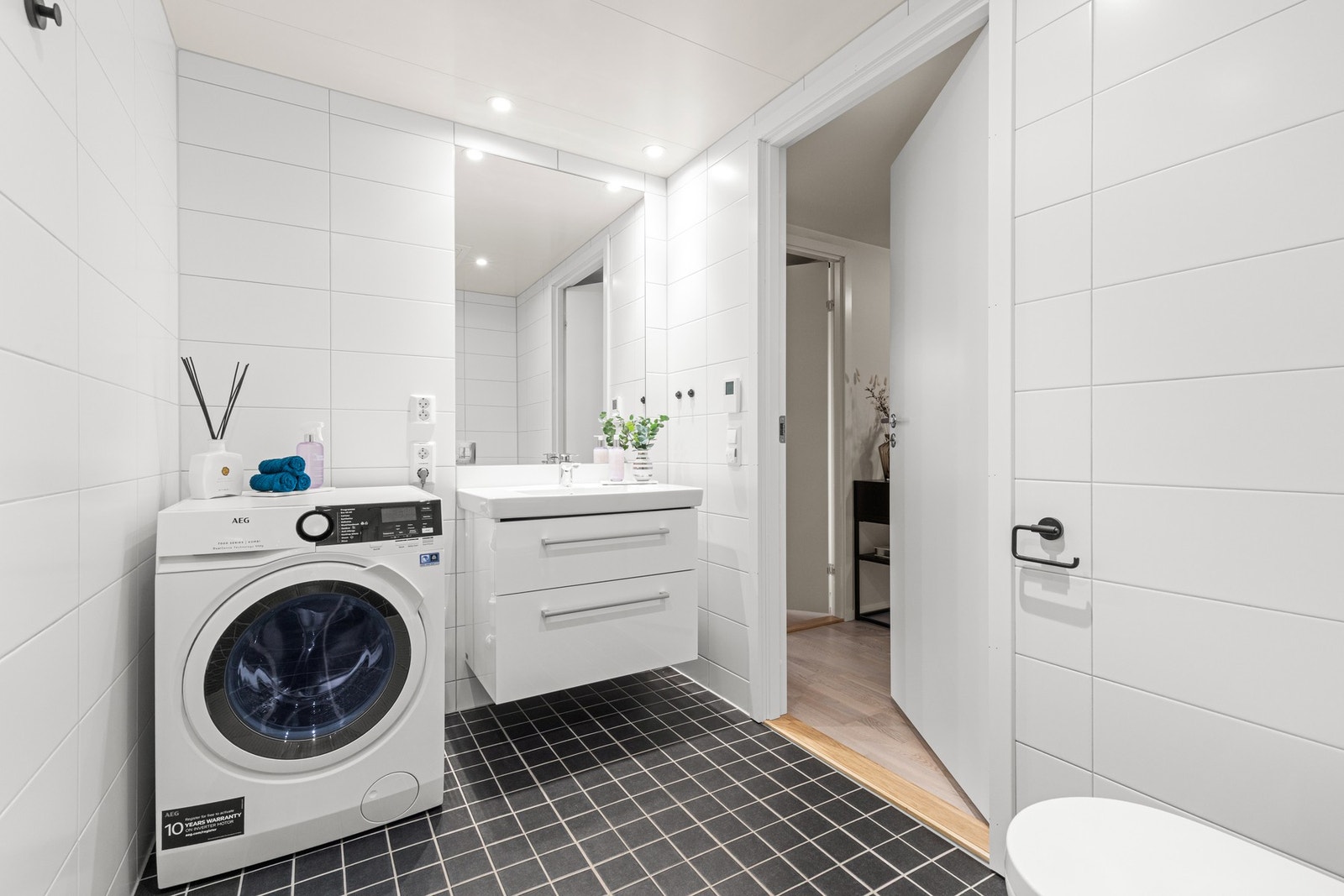 Baderoms innredning med glatte fronter, servant og opplegg til vaskemaskin. Galleribilde