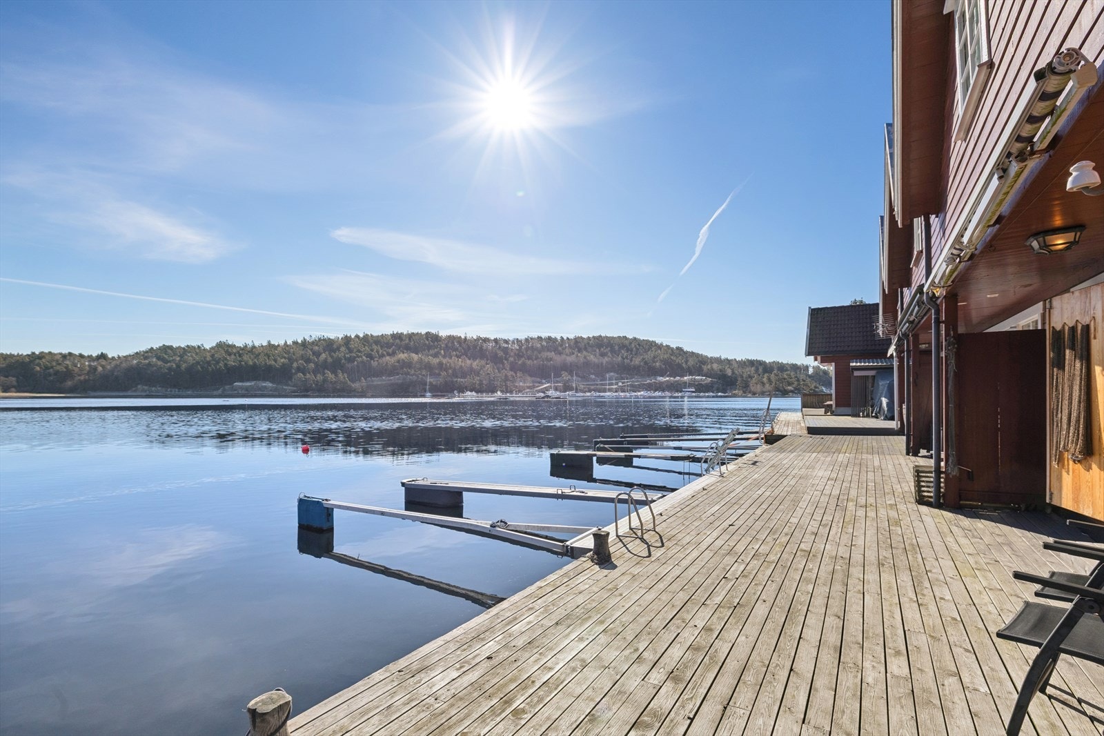Bryggen og sjøbua ligger i le for vær og vind, med nydelige solforhold. Galleribilde