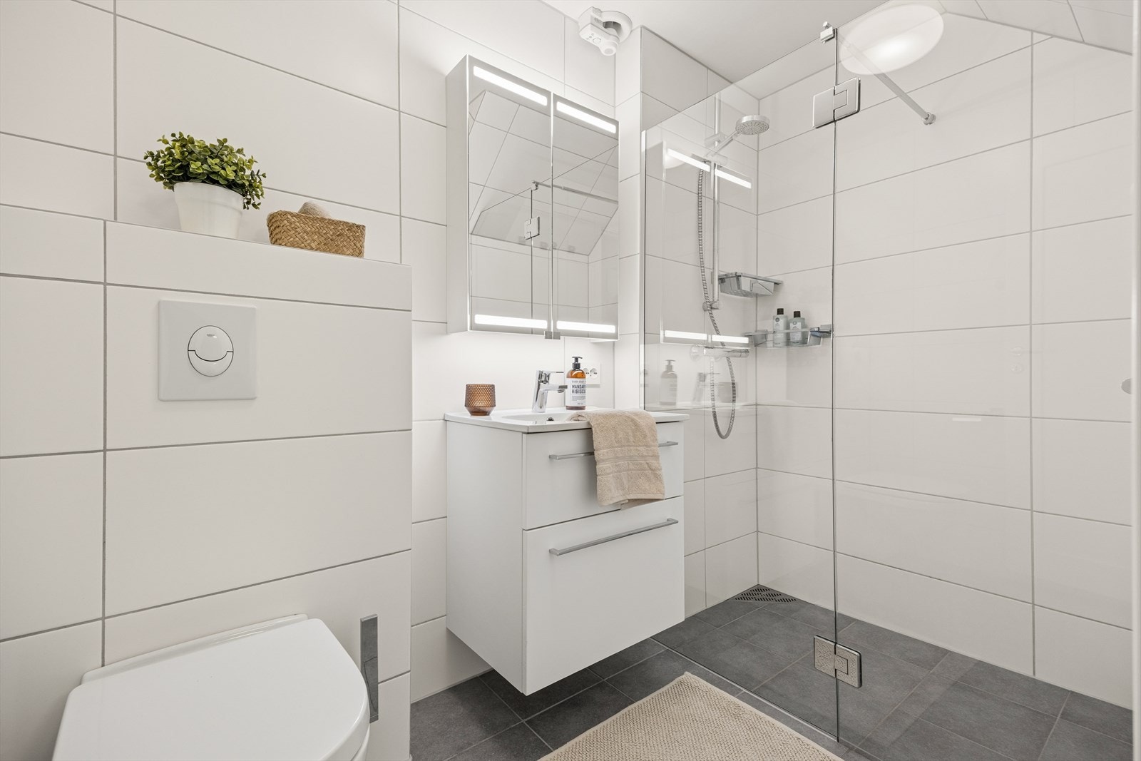 Badet har elektriske varmekabler i gulvet, vegghengt toalett og dusjhjørne med glassdører. Galleribilde