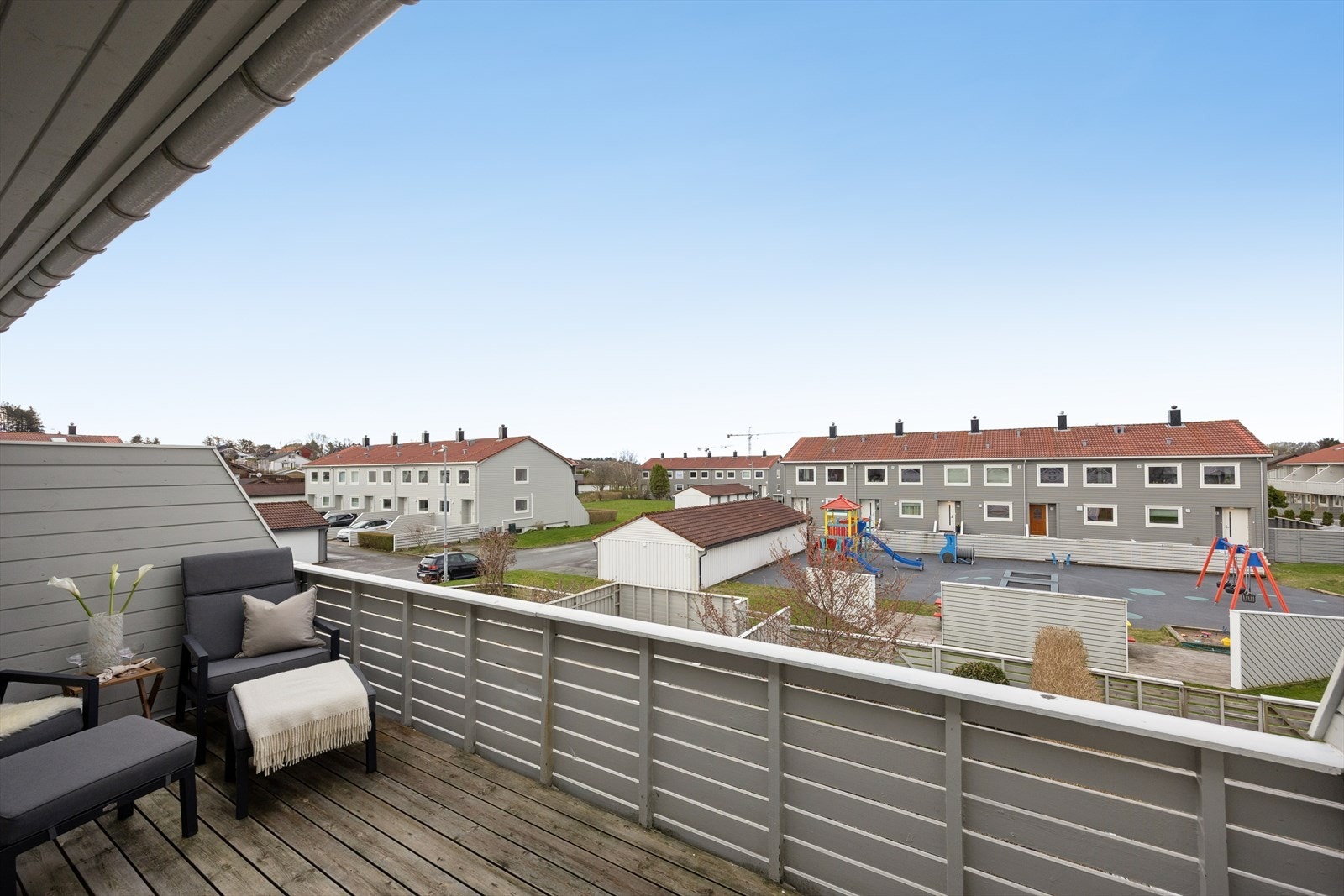 Fra balkongen ser du ut over borettslagets fellesarealer med lekeplass. Galleribilde