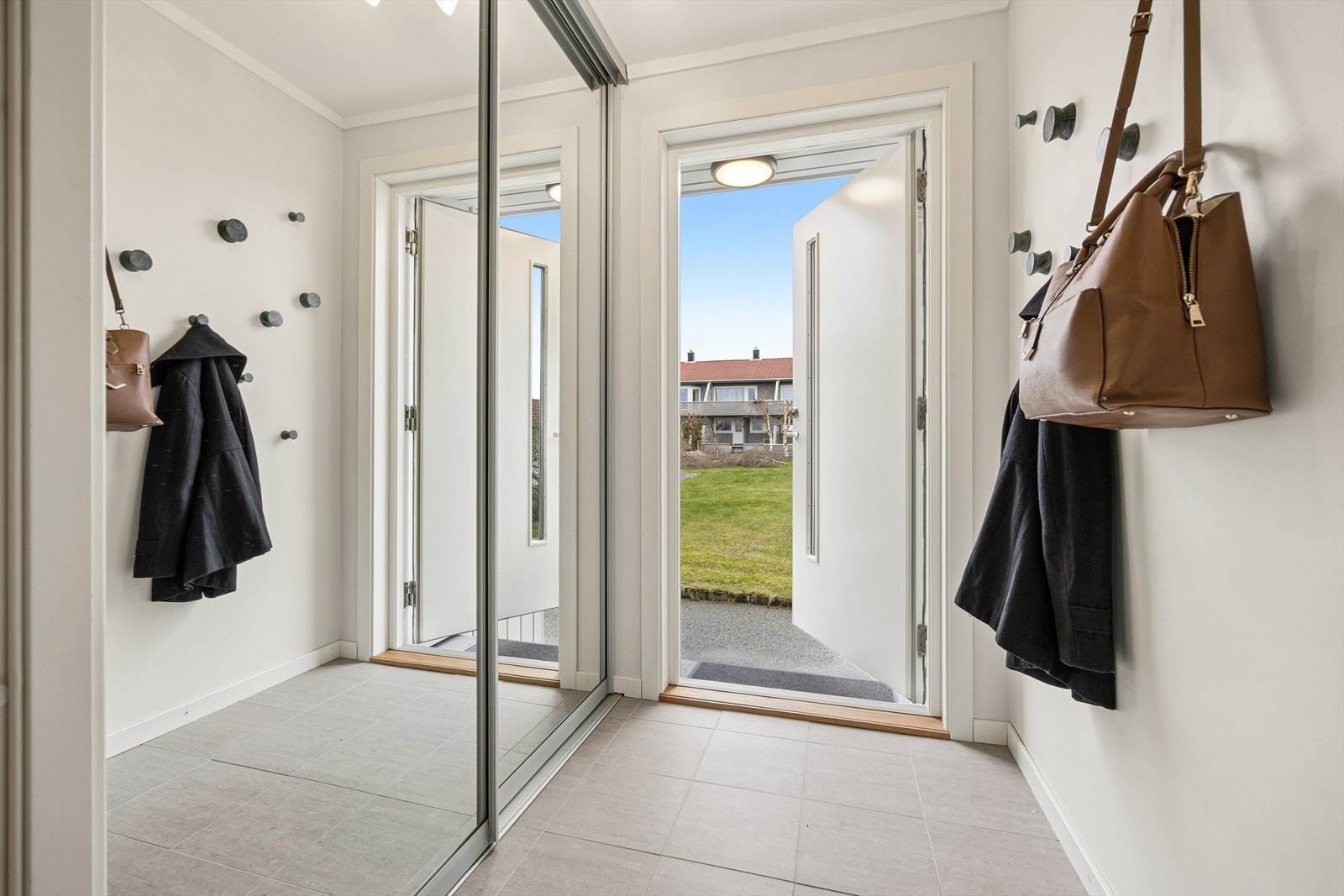 Entréen har flislagt gulv og en romslig skyvedørsgarderobe med speilfronter, installert i 2016. Galleribilde