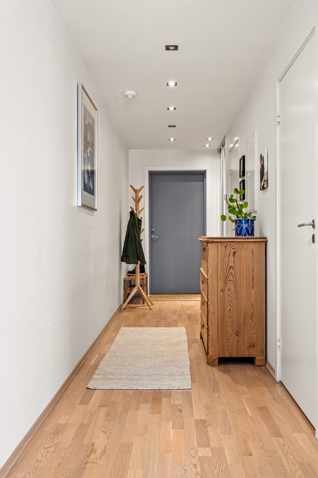 Romslig entré med skyvedørsgarderobe og parkett på gulvet. Galleribilde