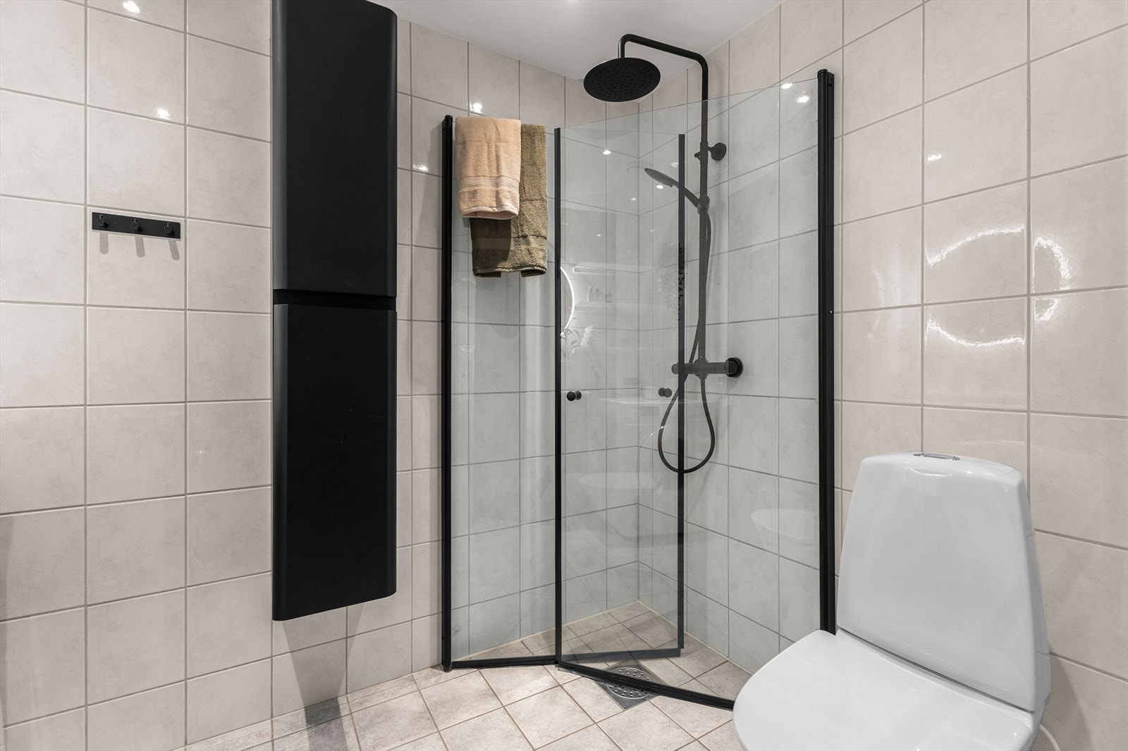 Badet er innredet med dusjhjørne med innfellbare glassdører, toalett og servantskap med nedfelt servant. Galleribilde