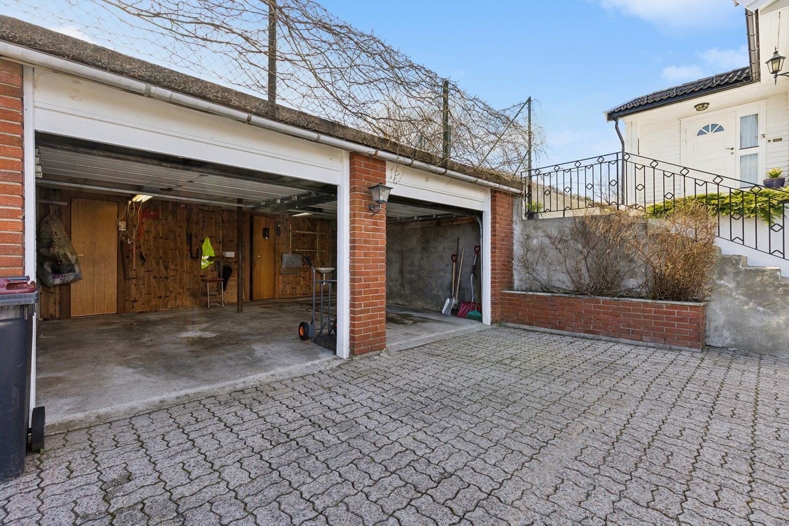 Garasjen er stor og dobbel med boder inne bak Galleribilde