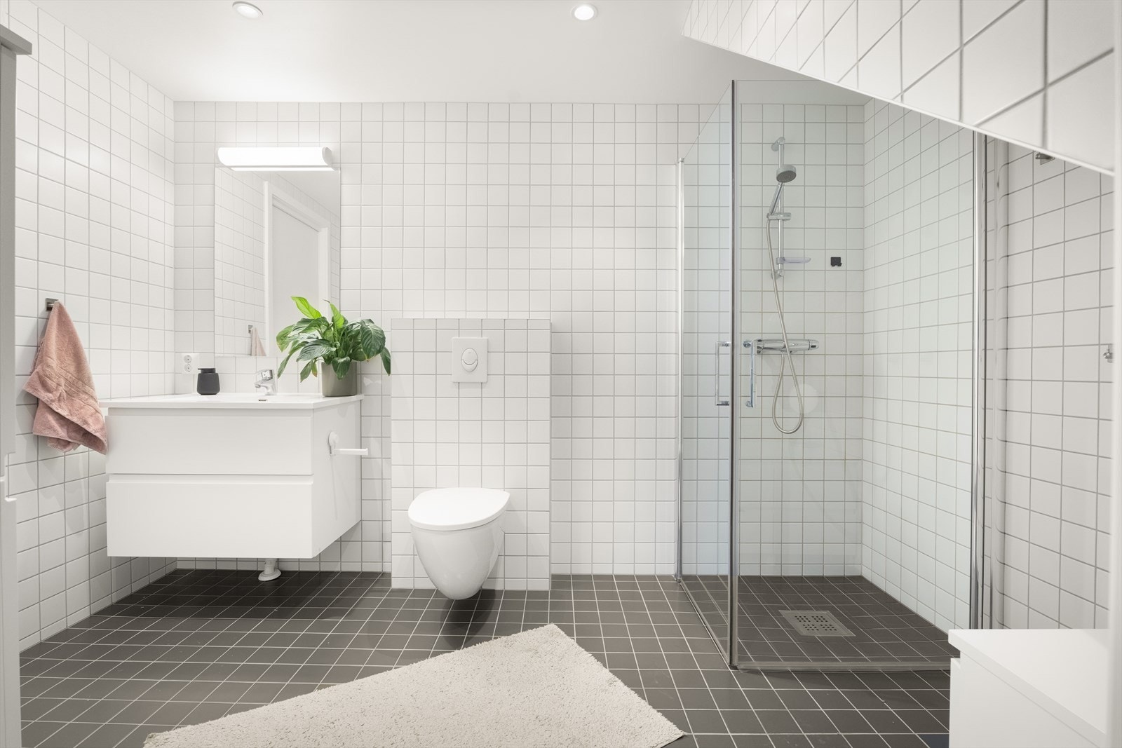 Badet i første etasje har flislagt gulv med varmekabler, vegghengt toalett og et romslig dusjhjørne med glassdører. Galleribilde
