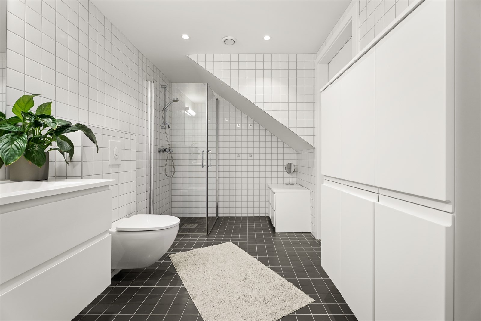Den smarte planløsningen utnytter plassen under trappen og kombinerer bad og vaskerom på en funksjonell måte. Galleribilde