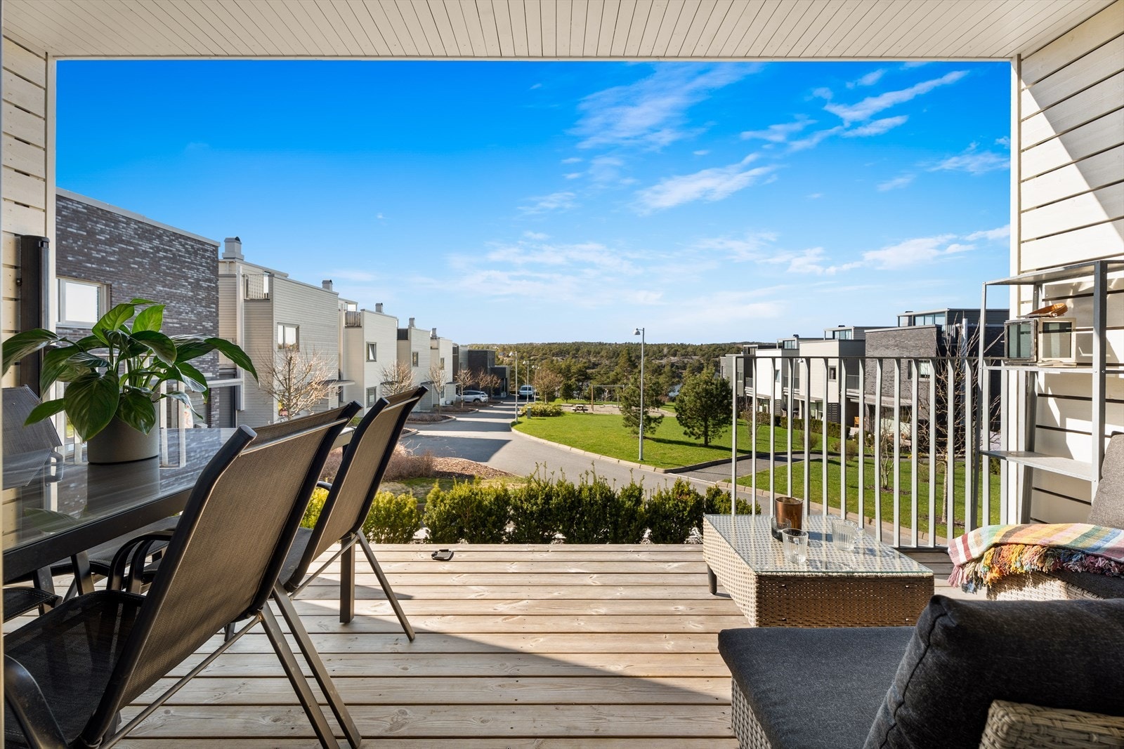 Terrassen har impregnerte terrassebord og et stilrent smijernsrekkverk, med utsikt over nabolaget. Galleribilde