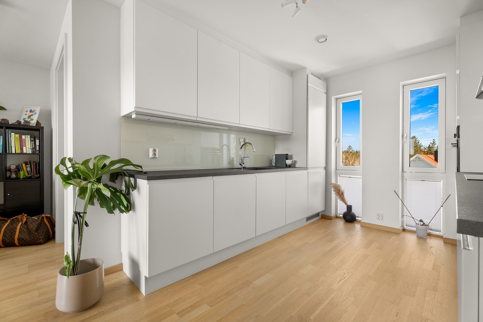 Kjøkkenet fra Aubo har hvite, slette fronter og en slitesterk laminatbenkeplate, som gir et tidløst og funksjonelt arbeidsområde. Galleribilde