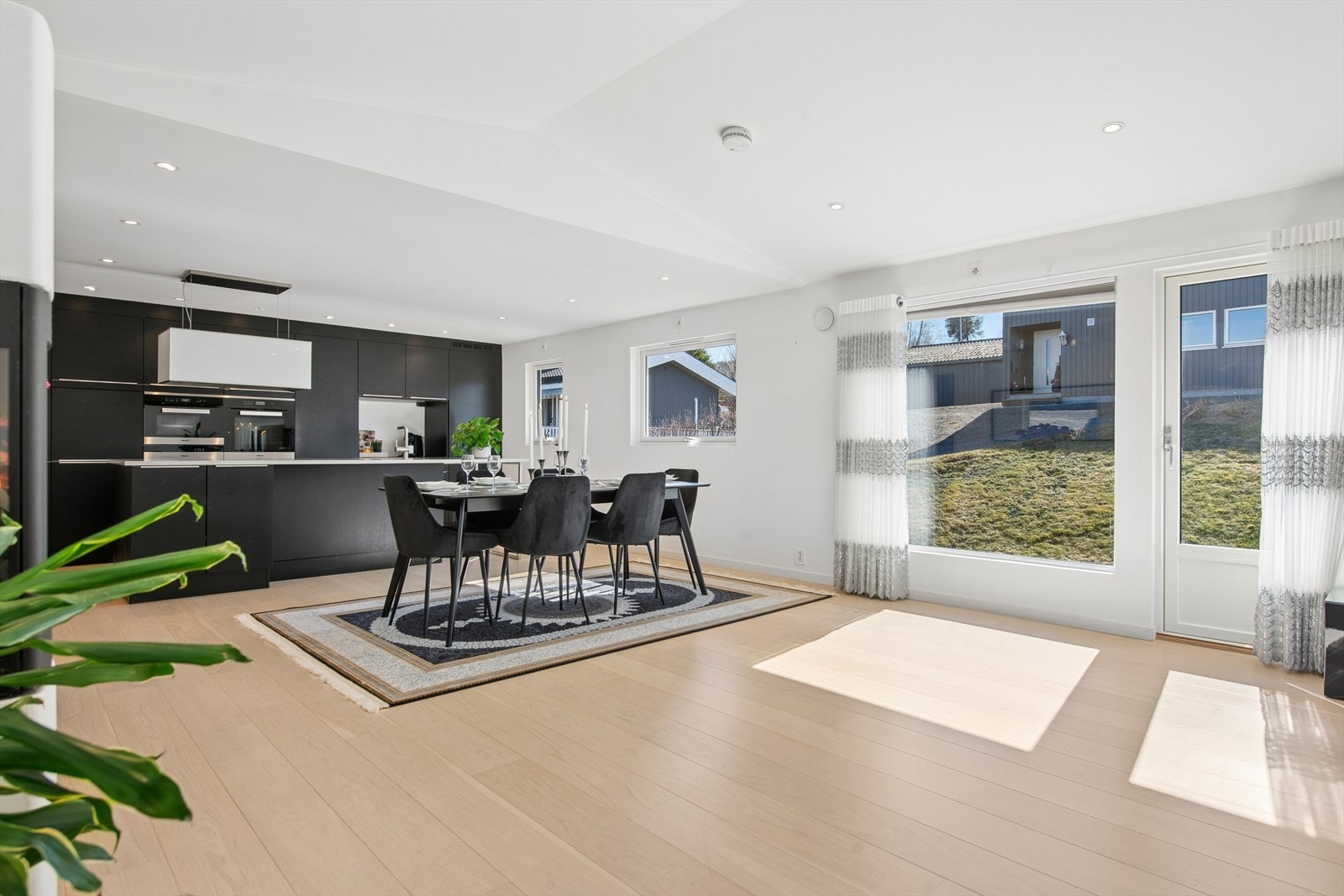 Kjøkkenet har en moderne innredning med sorte, glatte fronter og lys laminert benkeplate med nedfelt kjøkkenkum. Galleribilde