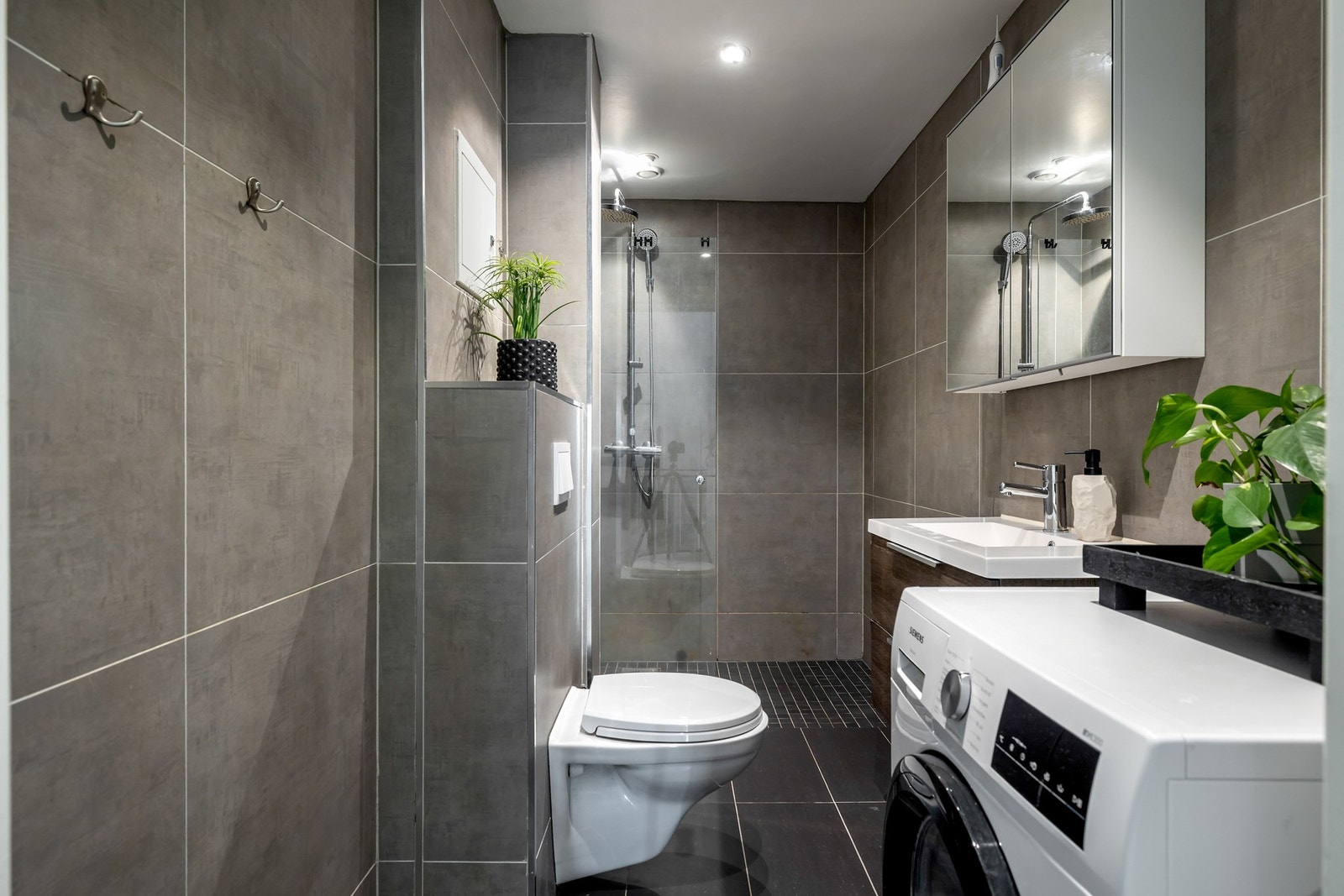 Badet i 1. etasje er fra 2016 og har flislagte vegger og gulv. Her er det også opplegg for vaskemaskin. Galleribilde
