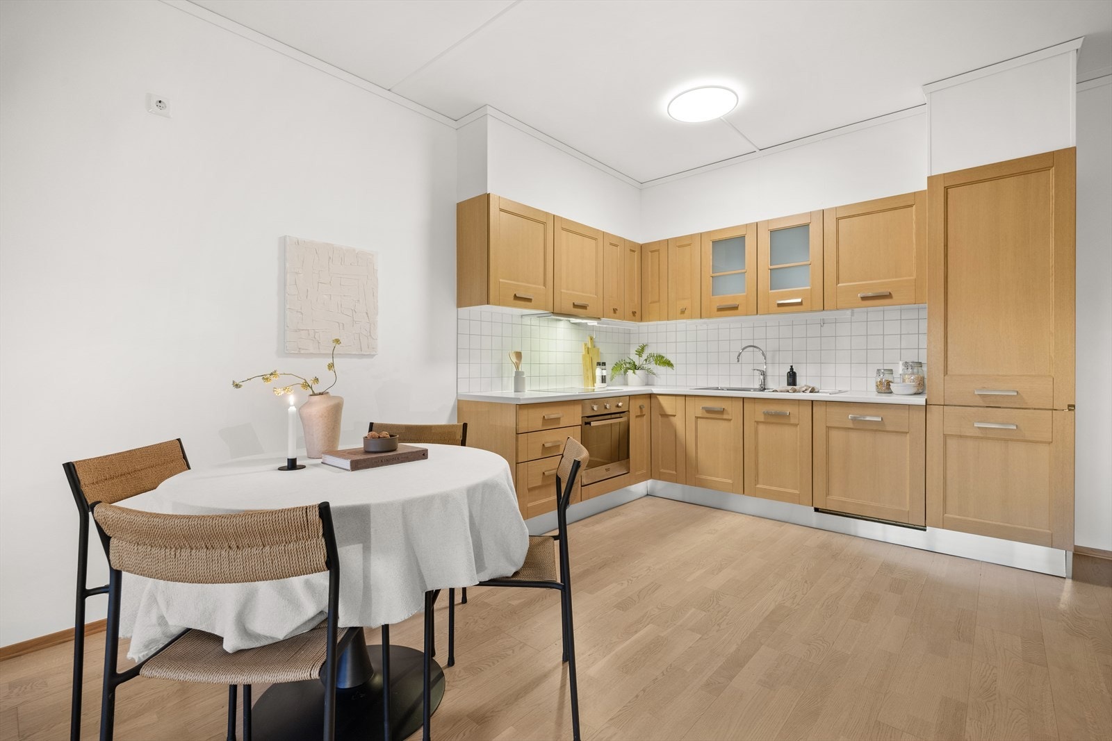 Kjøkkeninnredning langs to vegger med profilerte fronter og laminat benkeplate med dobbel kum. Galleribilde